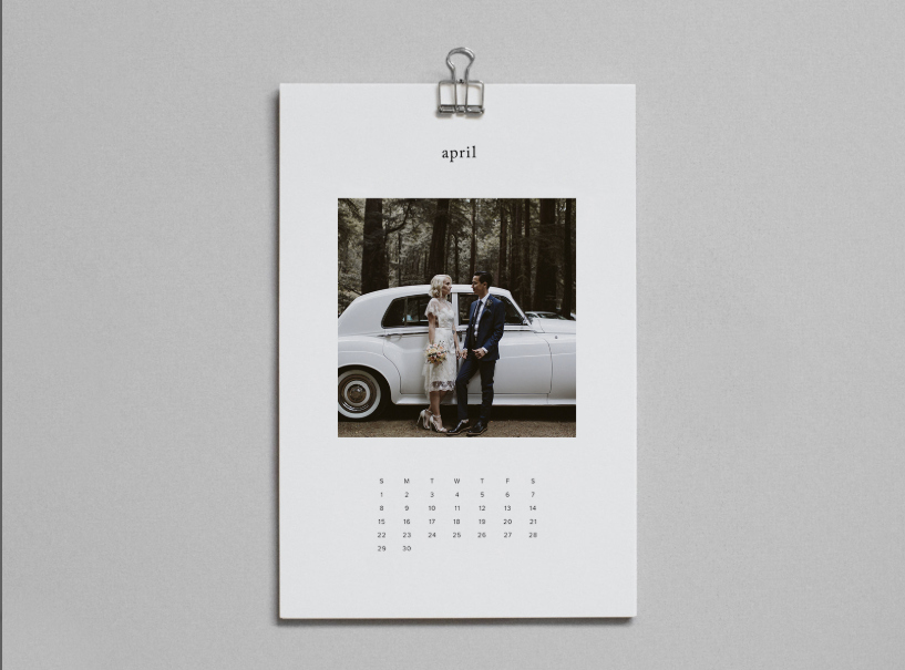 Monthly calendar on clip board with a large full body image of a couple. Monthly dates are below the image.
