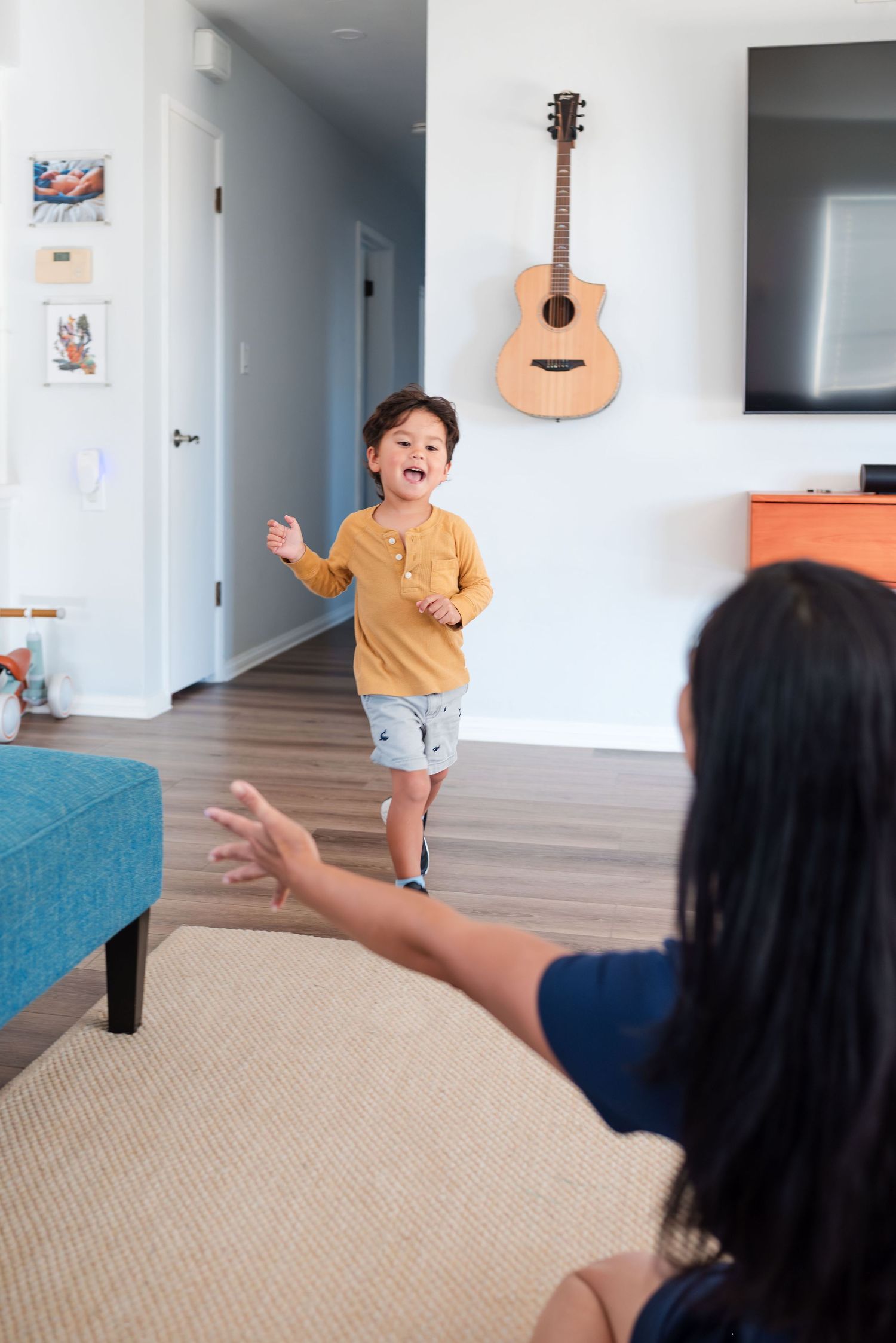 Toddler running toward his mother during a relaxed in-home family photo session.