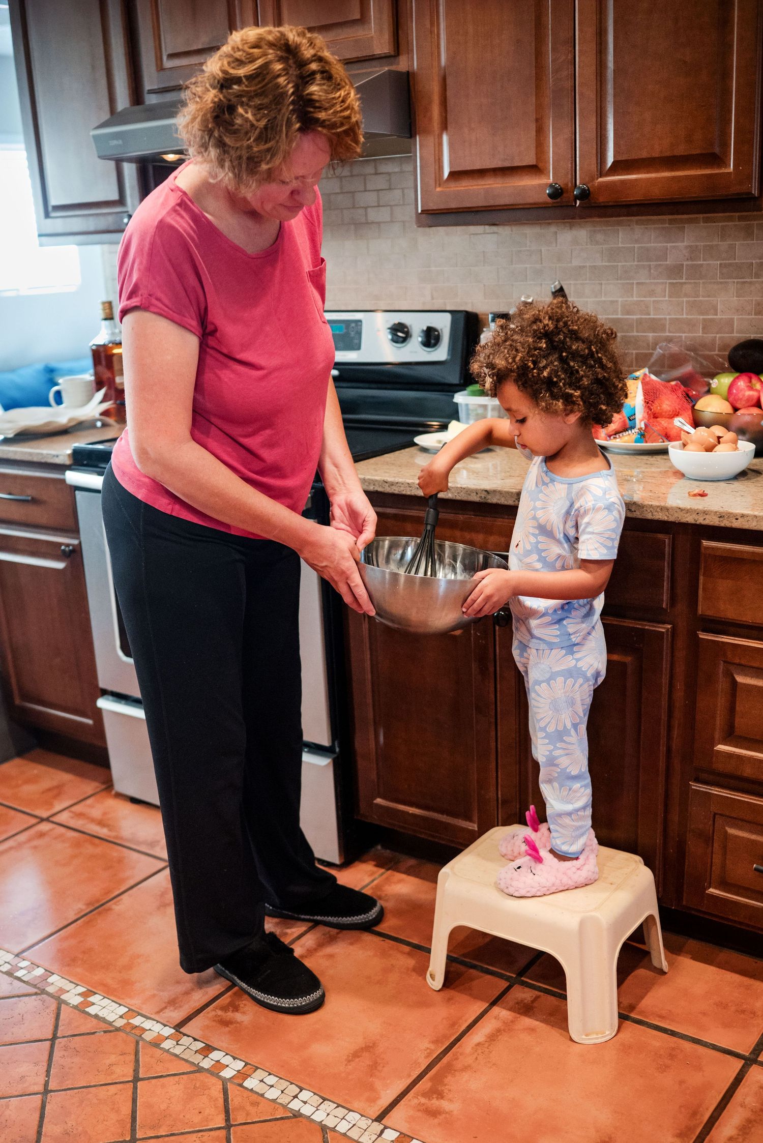 Mom holds the bowl at a lower level so her toddler daughter and whisk the eggs. In-Home family session. Doughman Photography.