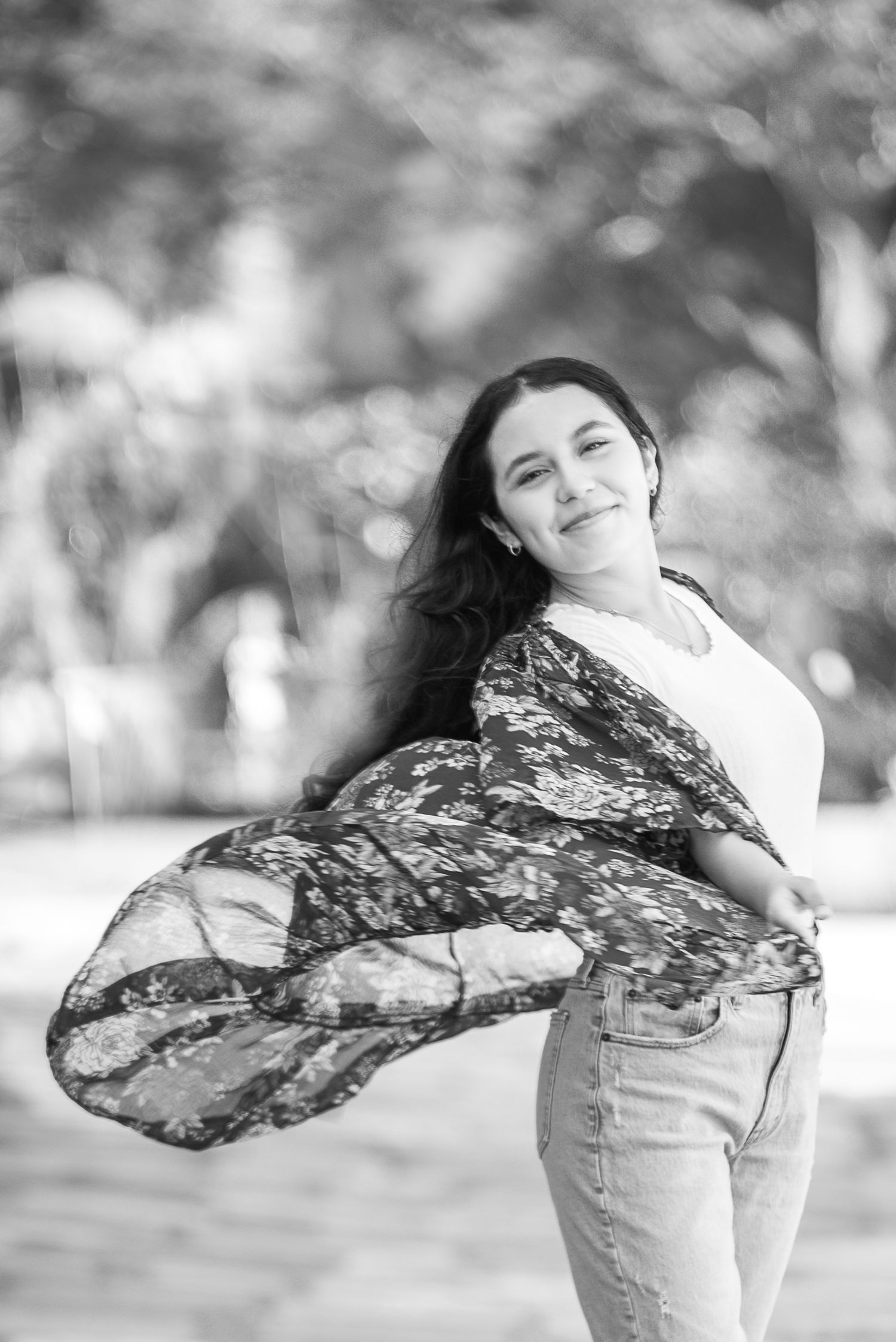 Black and white of young woman wearing a light wrap twirling. The wrap lifts in the air creating movement.  Doughman Photography
