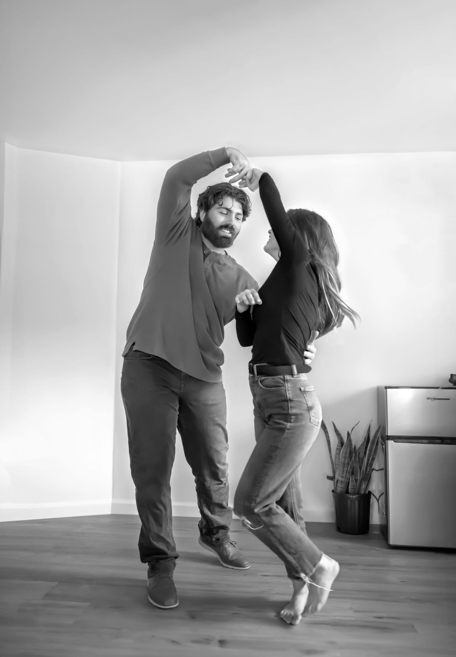 Couple dancing in their empty kitchen celebrating new home purchase. Black and white. In-Home couples photography. Doughman Photography.