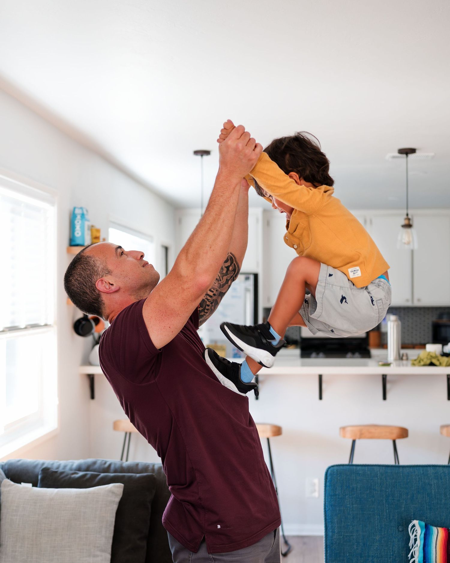 Father lifting his toddler while playing during an in-home family photography session.