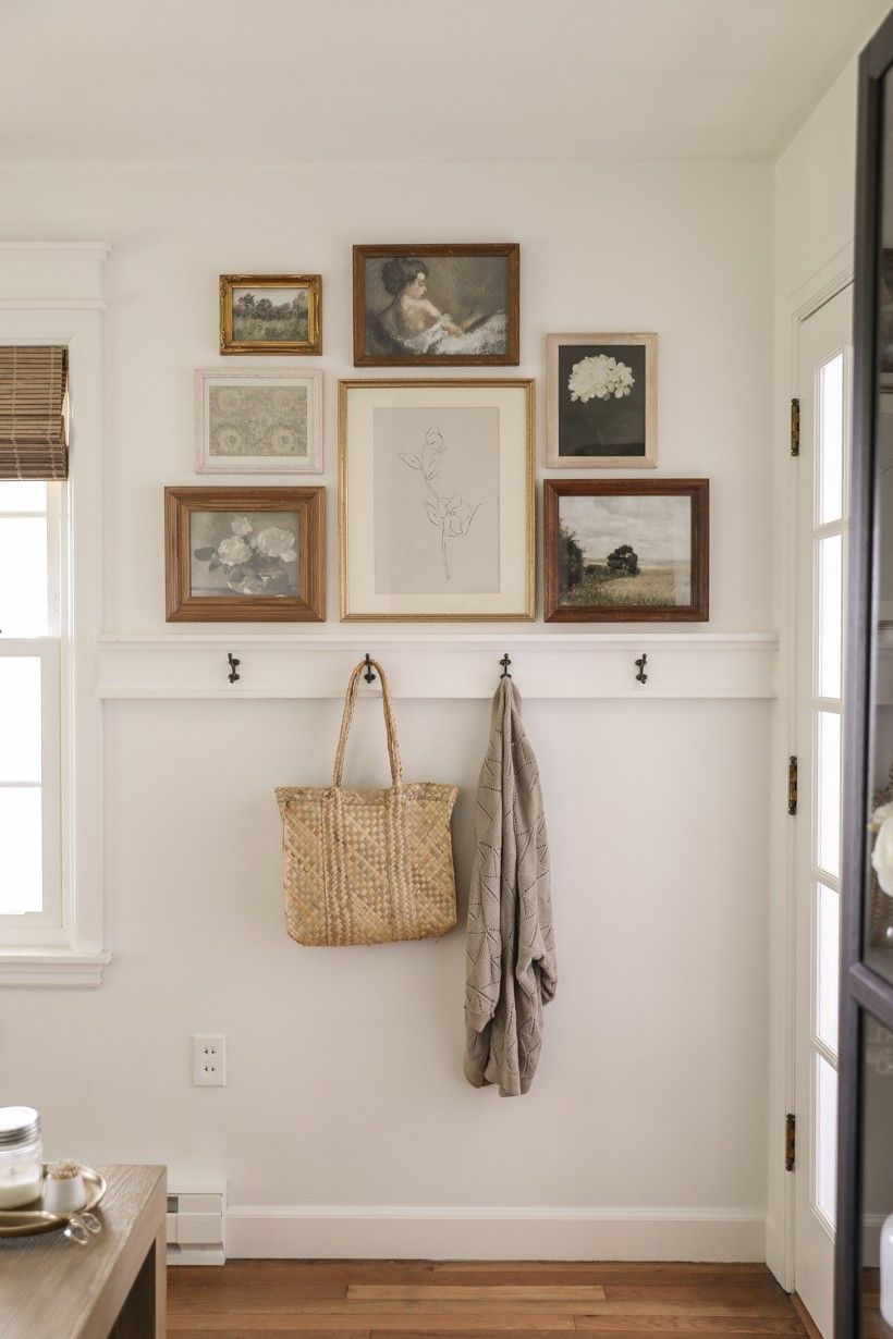 Entryway gallery wall with seven framed images and artifacts above four wall mounted coat hooks. Doughman Photography.