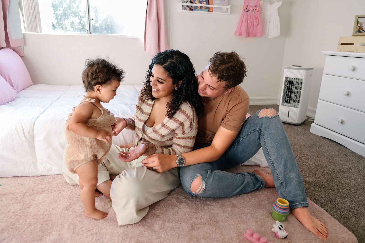 A young toddler takes wobbly steps into mom and dad's arms. Doughman Photography