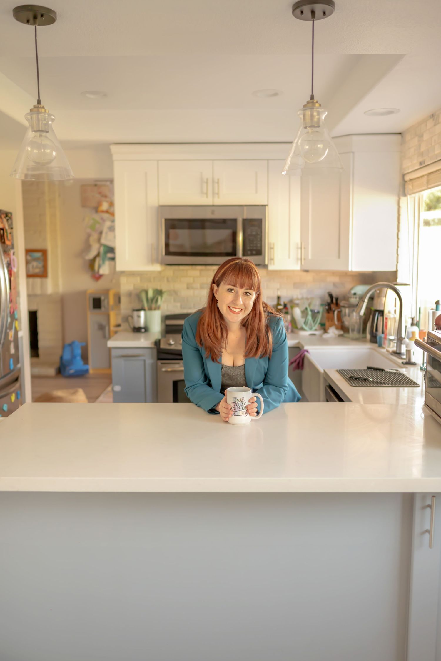 Professional woman leaning against kitchen island holding a coffee cup. In-Home Branding Session for small business. Doughman Photography.