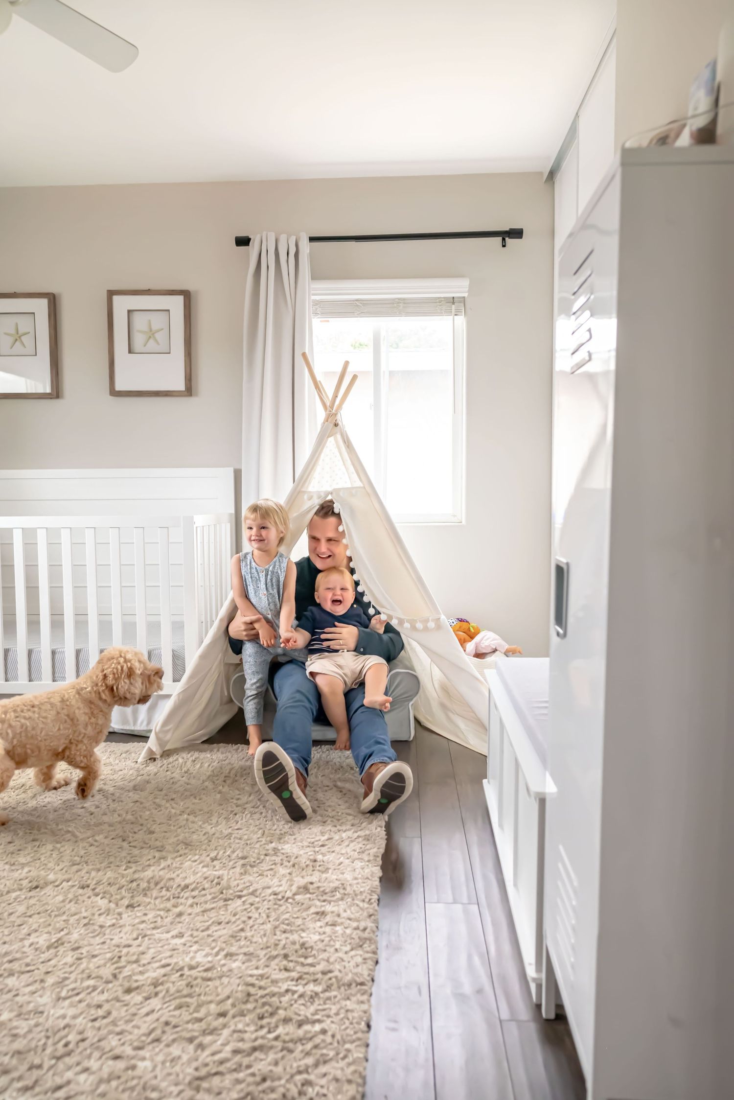 Dad sits in kids play tent with two kids in the kids room. A fluffy poodle tries to join in. In-Home Family Photography with Pets. Doughman