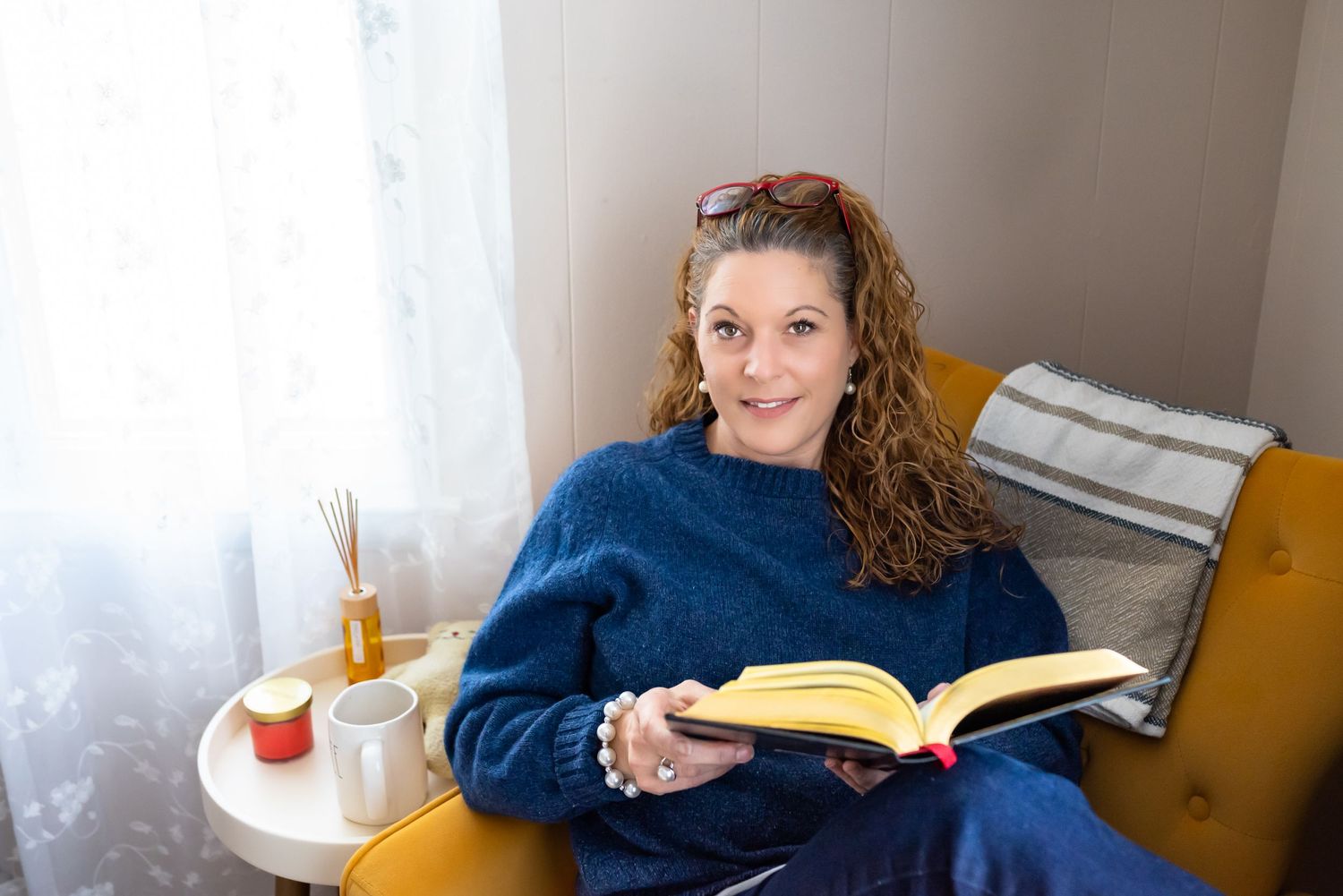 Woman in dark blue sweater sitting in mustard color lounge chair illustrating the cool and modern color palette. Doughman Photography.