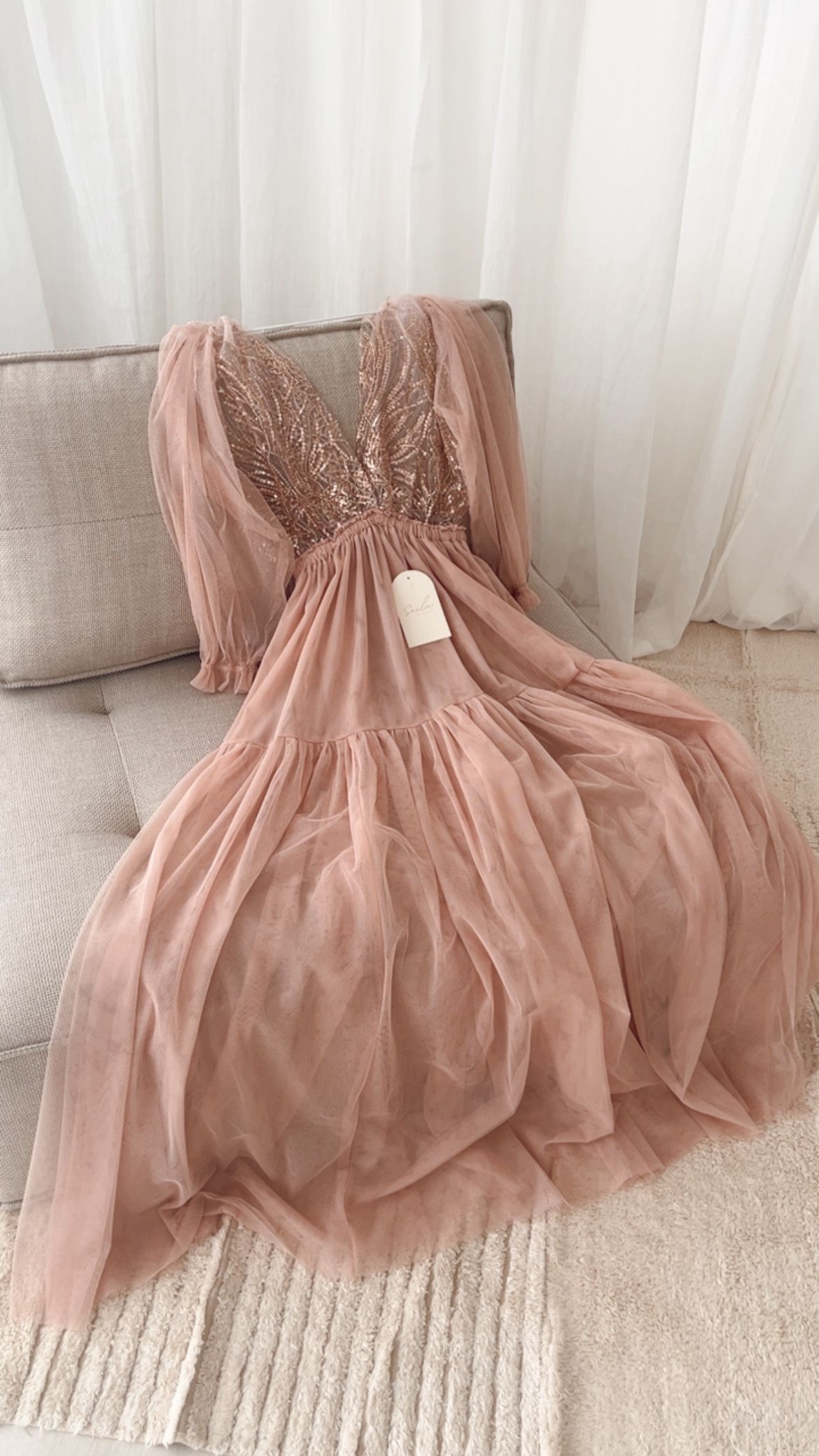 A delicate dusty pink tulle dress with beaded embellishments shown from different angles on a light carpet.