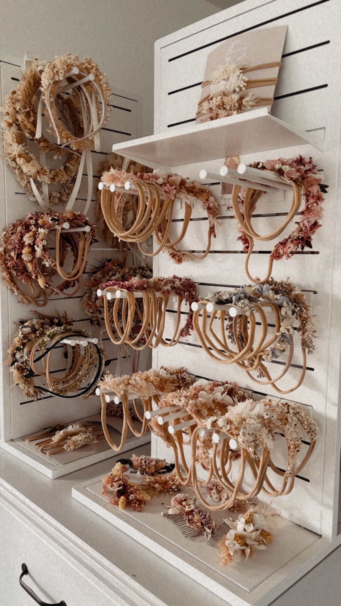 Multiple rustic chandeliers with floral decorations displayed on white shelving in a retail store setting.