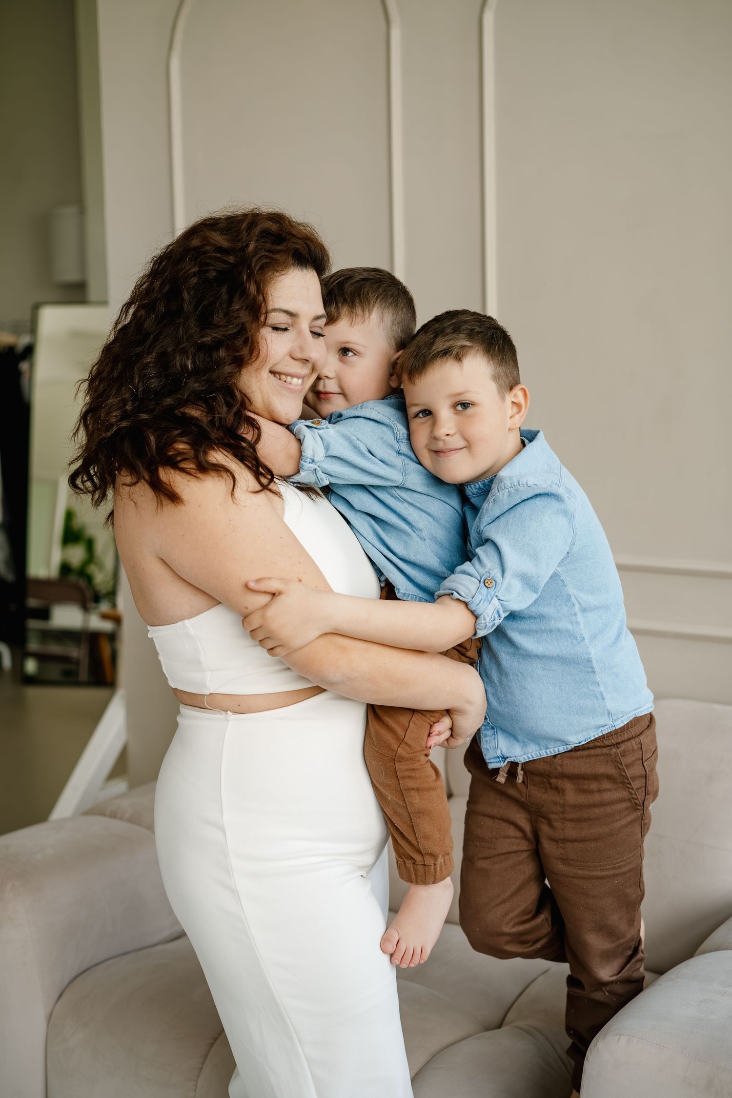A loving moment captured in white dress and blue shirt as mother and child share tender embraces on a couch.