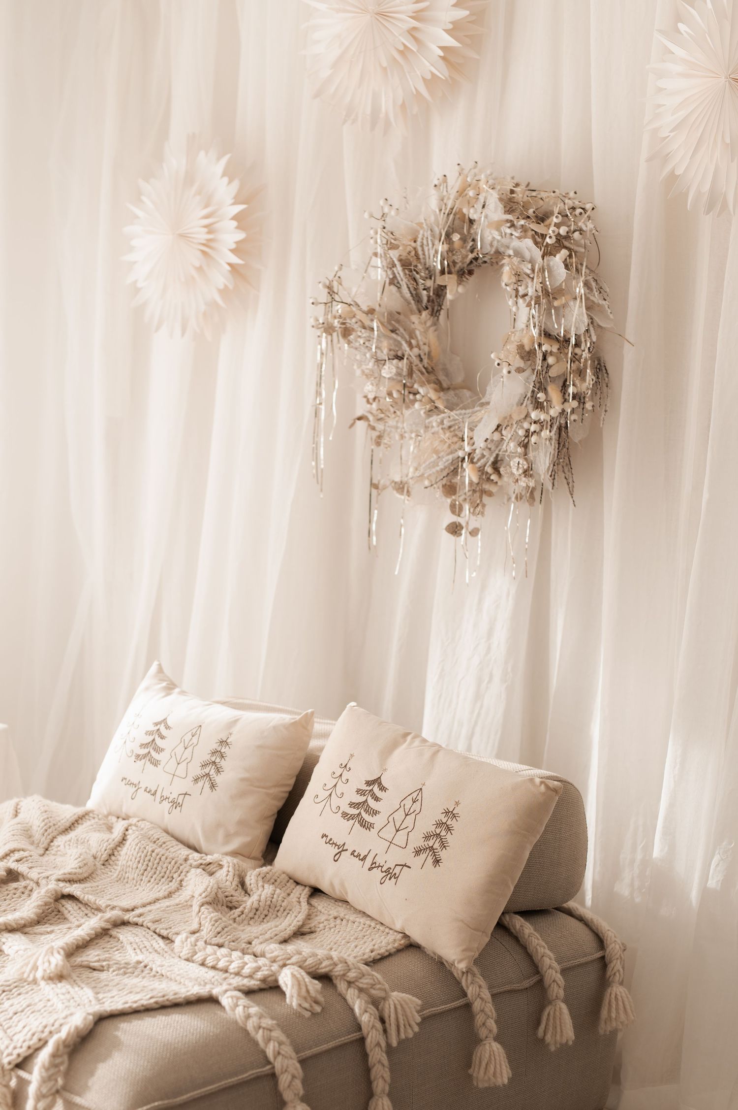 Cozy boho bedroom decor with neutral beige pillows and macrame wall hangings in soft ethereal lighting.
