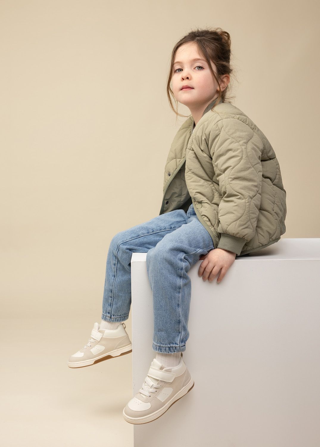 Young girl with brown hair in green jacket posing in a studio for a model update shoot