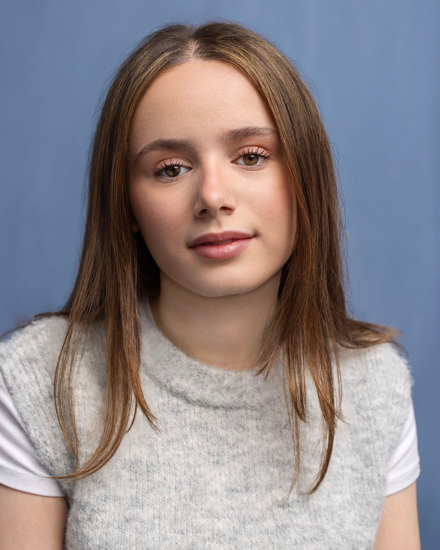 young woman in grey top, blue background:
Actor headshot photographed at Abigail Stewart Photography studio in Buckinghamshire