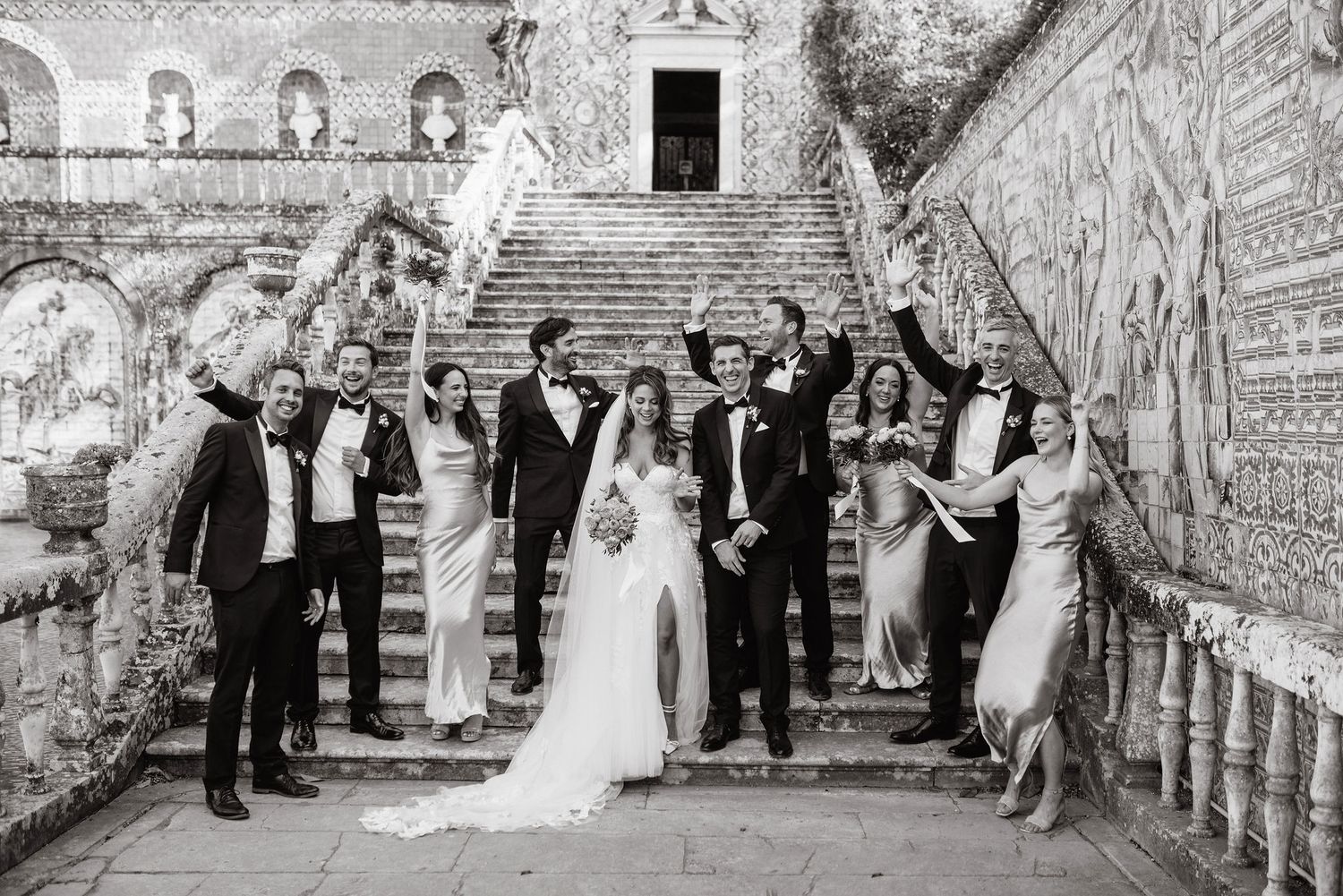 Bride and groom with the wedding party at the stairs of elegant Fronteira Palace in Lisbon on the wedding day.