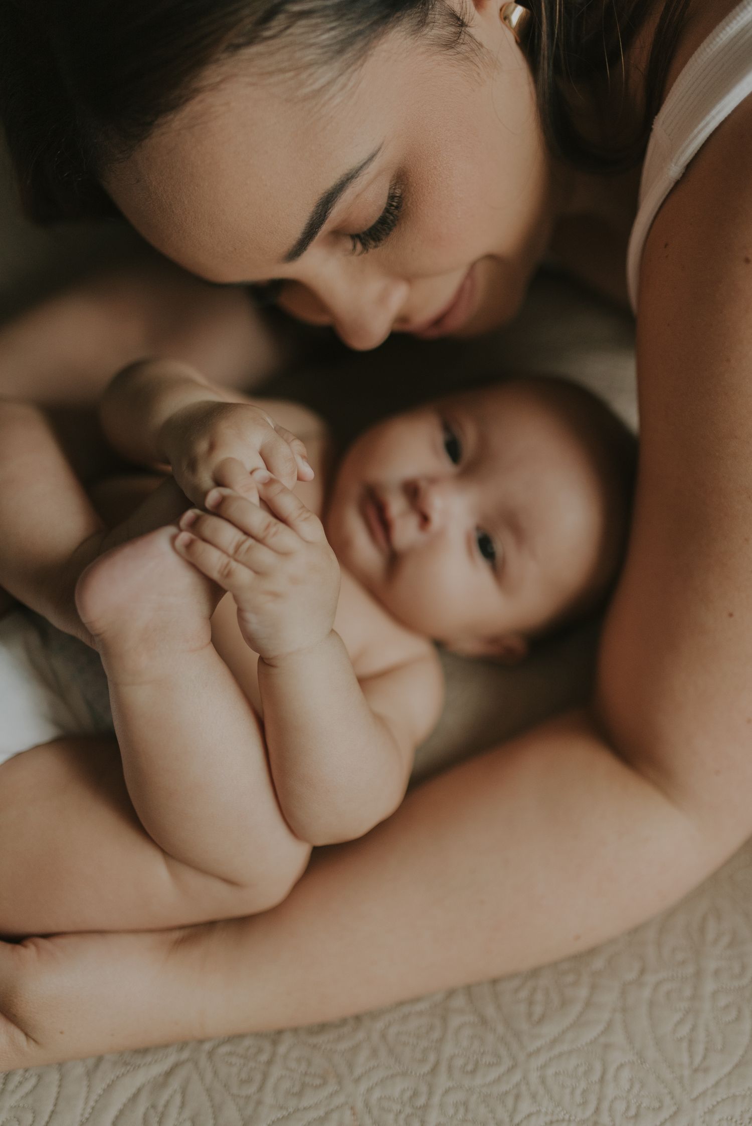 Intimate portrait of tender moments between parent and baby lying together.
