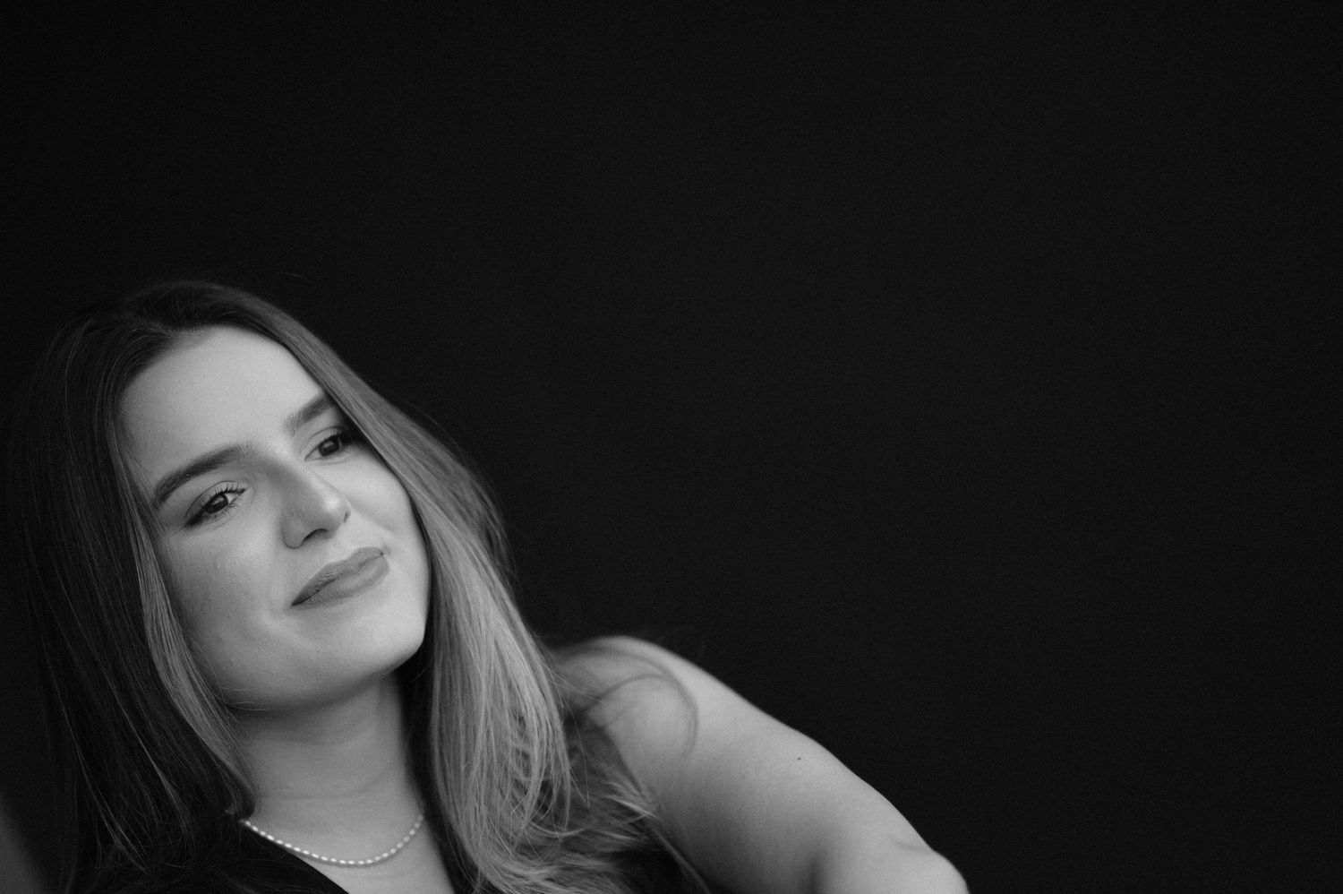 Side-lit black and white portrait with gentle expression against dark background.