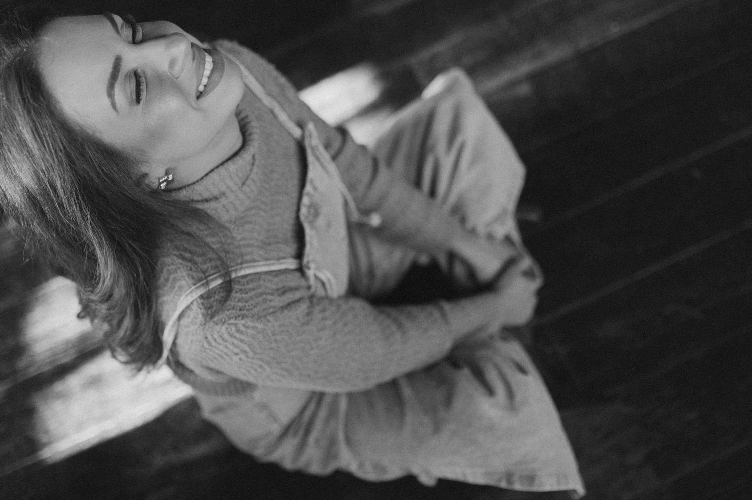 Black and white portrait of someone smiling while looking up in casual attire.