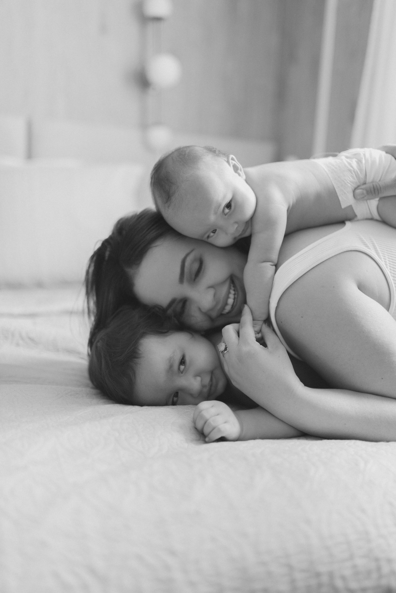 Black and white image of peaceful family cuddle time on bed.