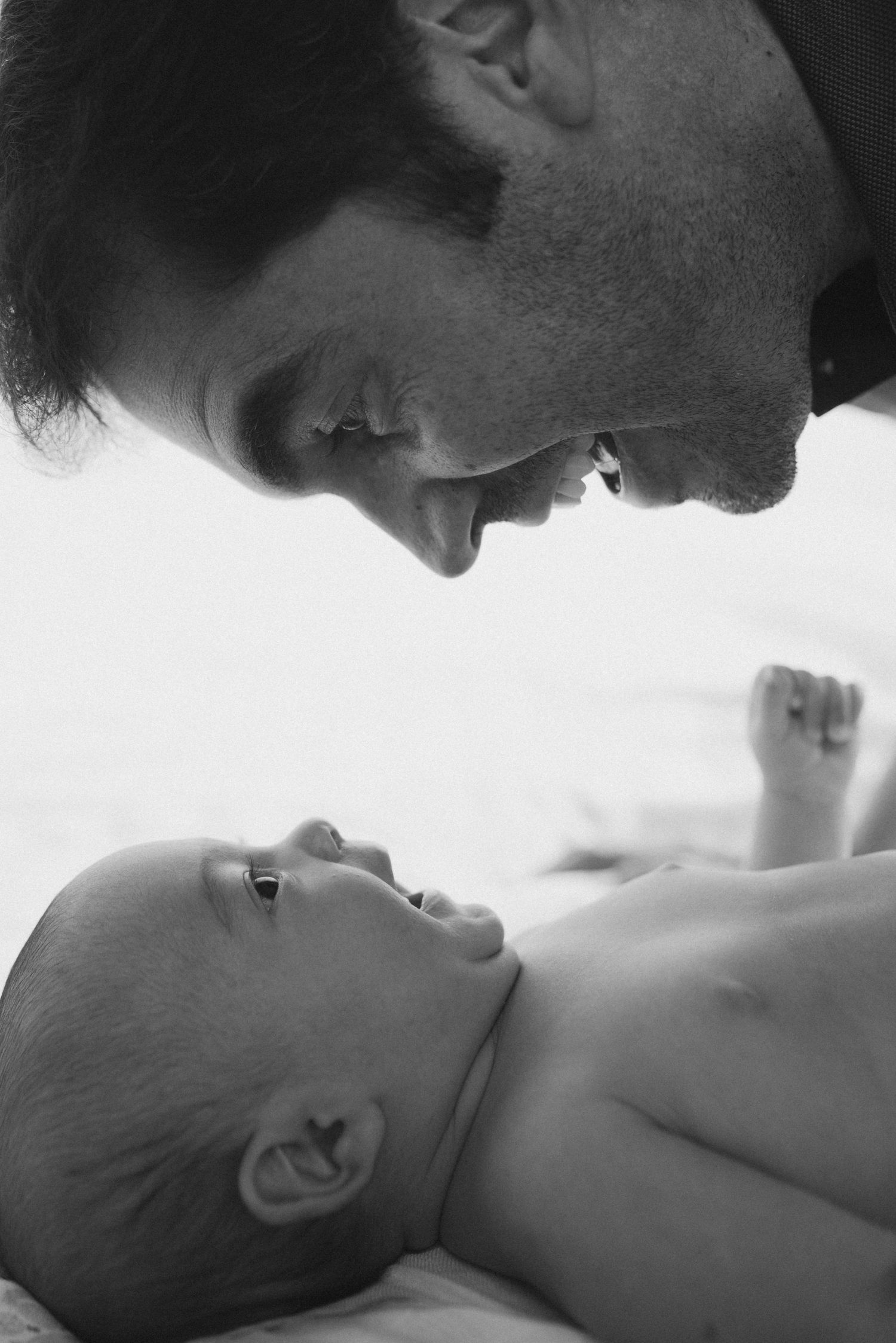 Intimate black and white close-up of parent and baby gazing at each other.