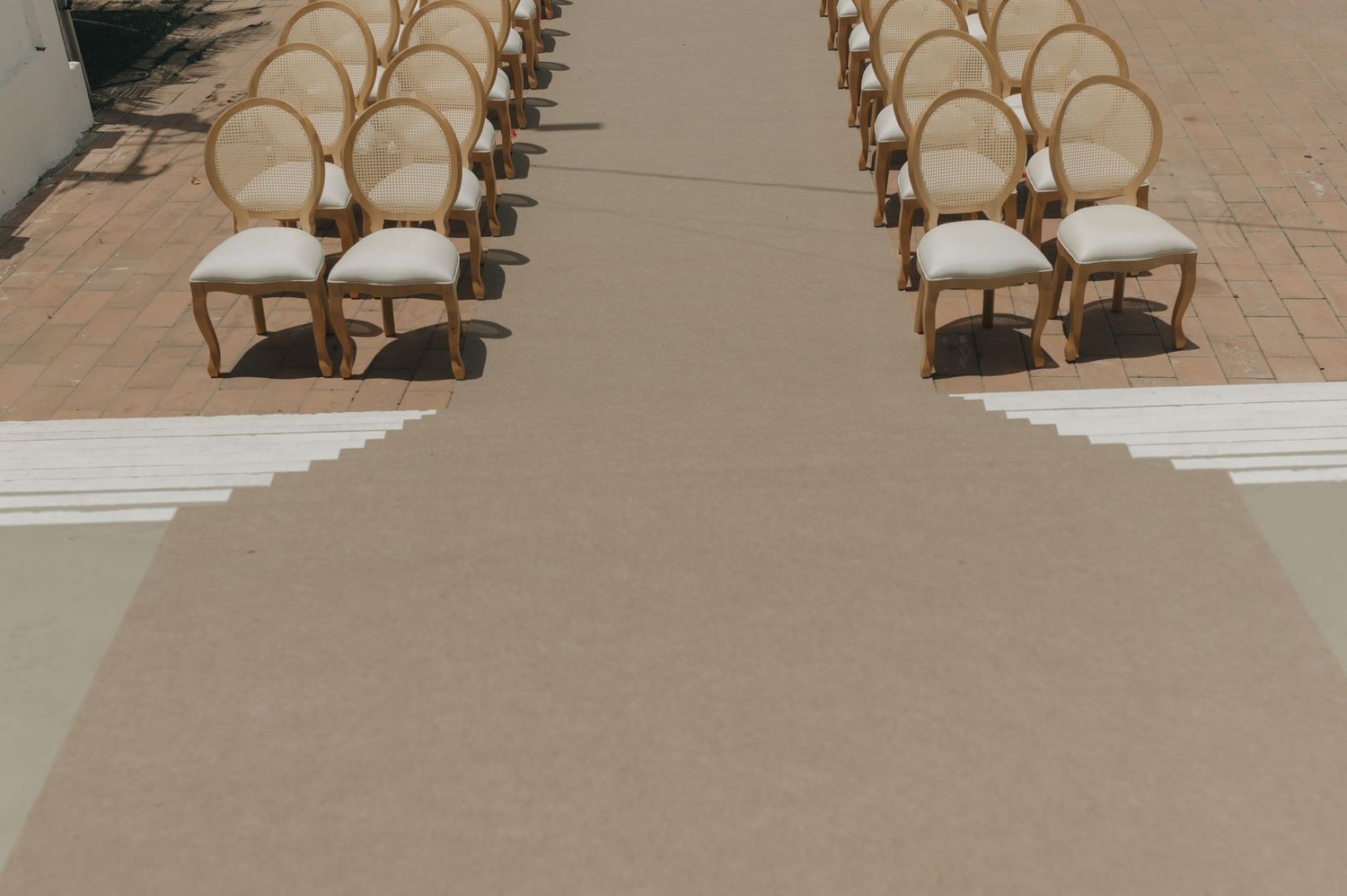 Elegant wedding ceremony setup with rows of wooden chairs and a neutral aisle runner.
