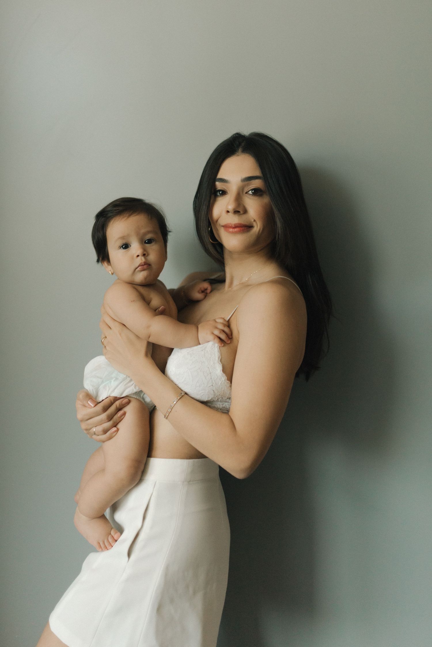 A mother and baby share intimate moments in white against a neutral background in a series of connected photos.