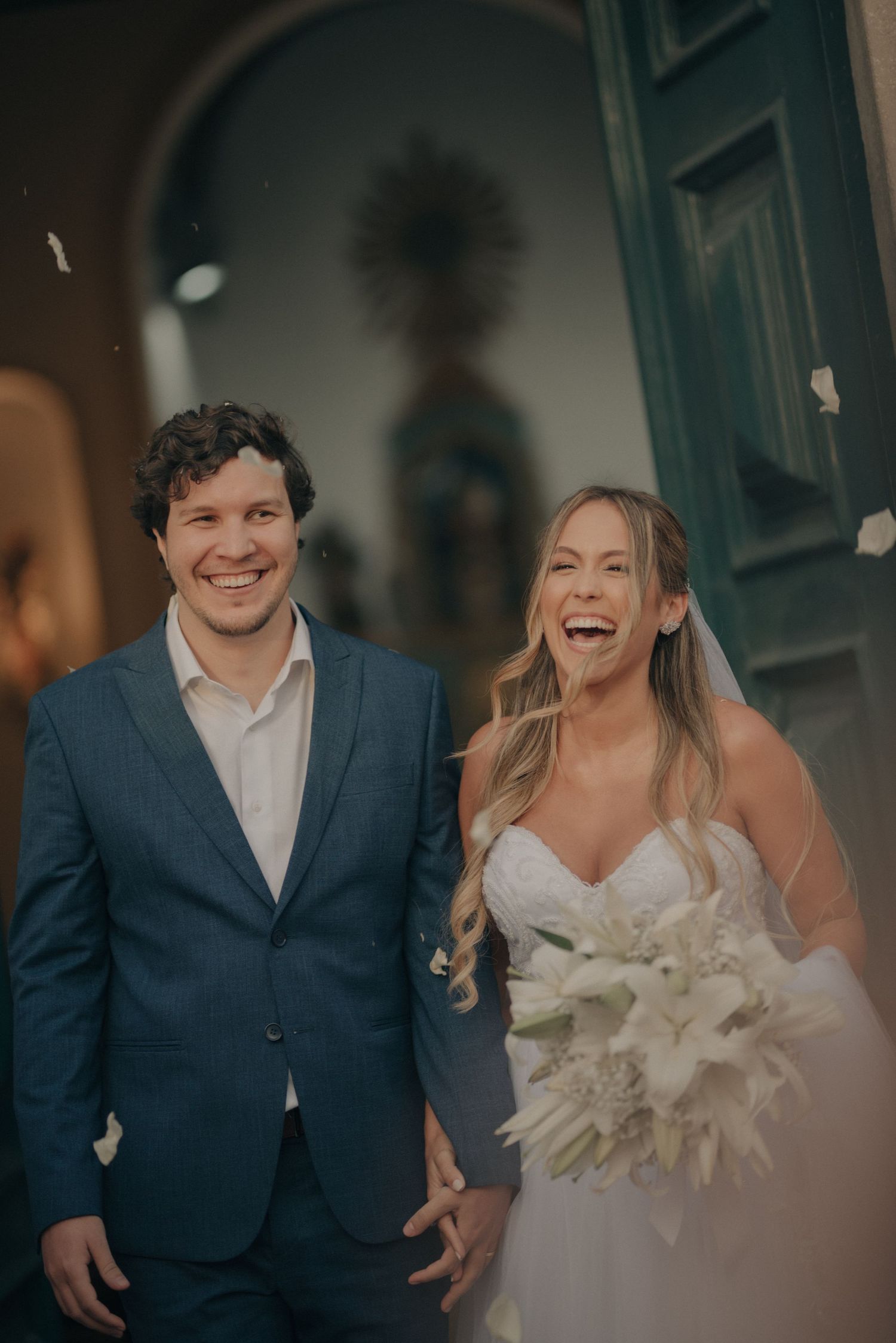 A joyful newlywed couple share a candid moment outside a blue door.