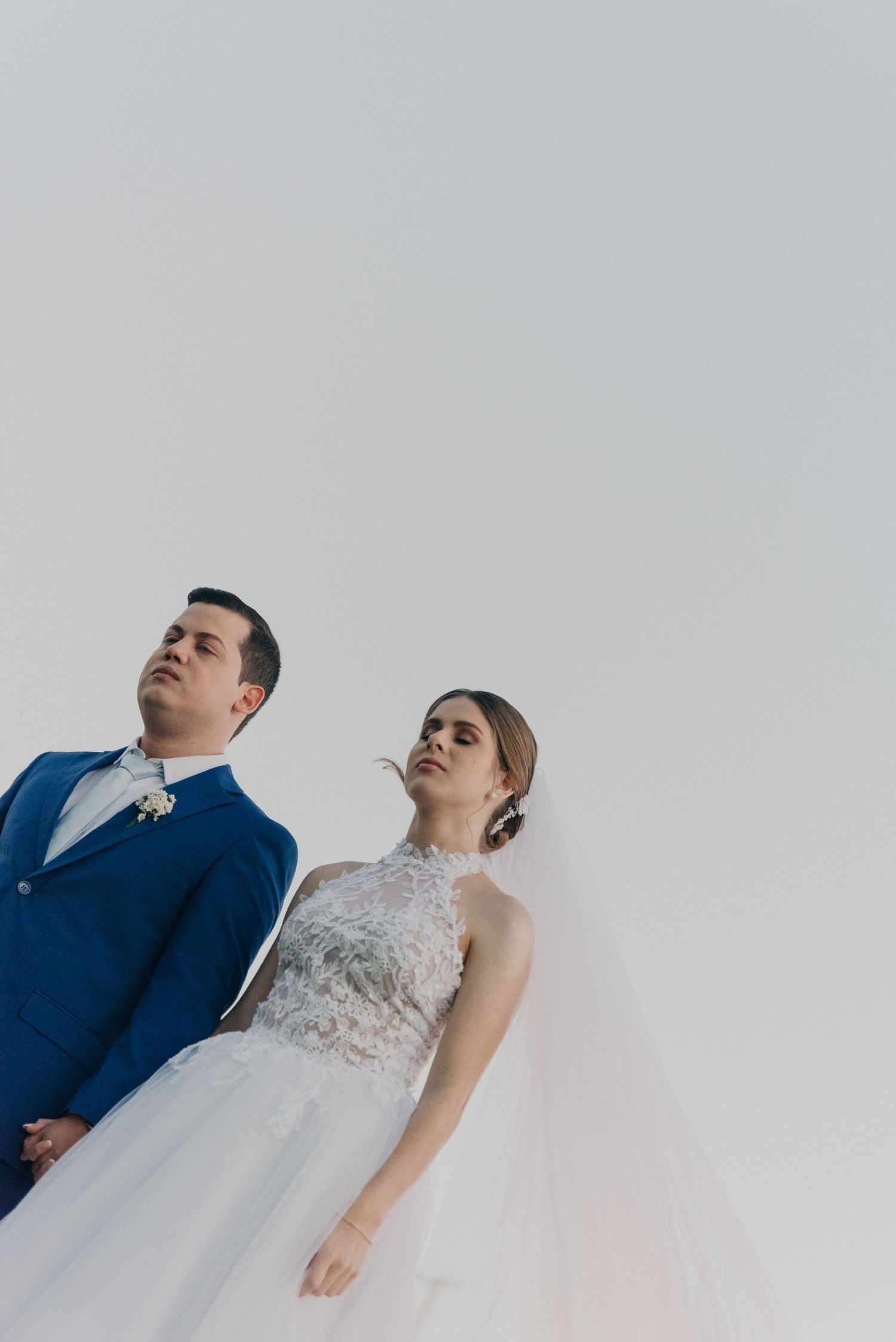 Minimalist wedding portrait against grey background showing bride and groom in formal attire.