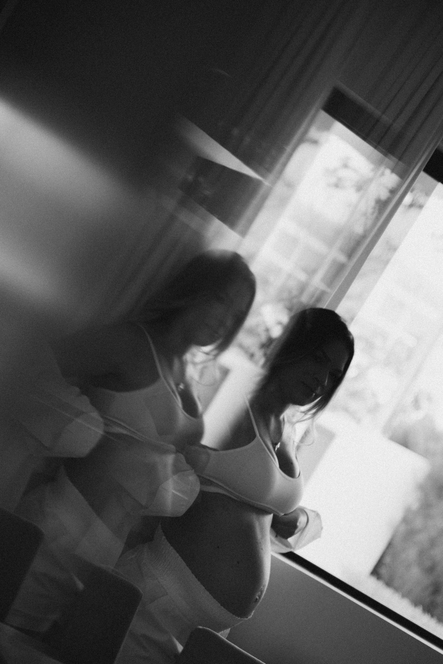 Black and white artistic maternity silhouette by window.