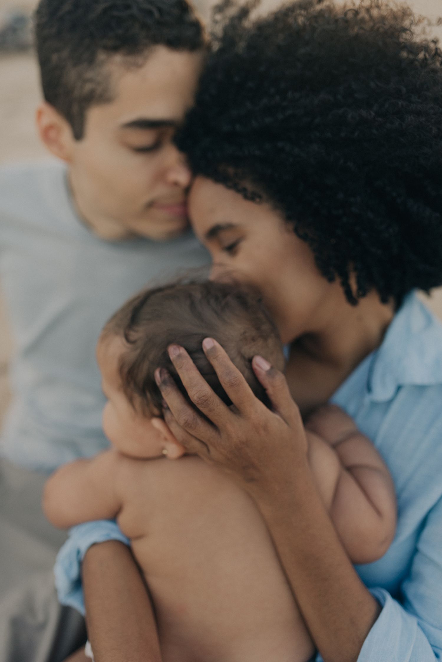 Intimate family moment as parents embrace their baby together.