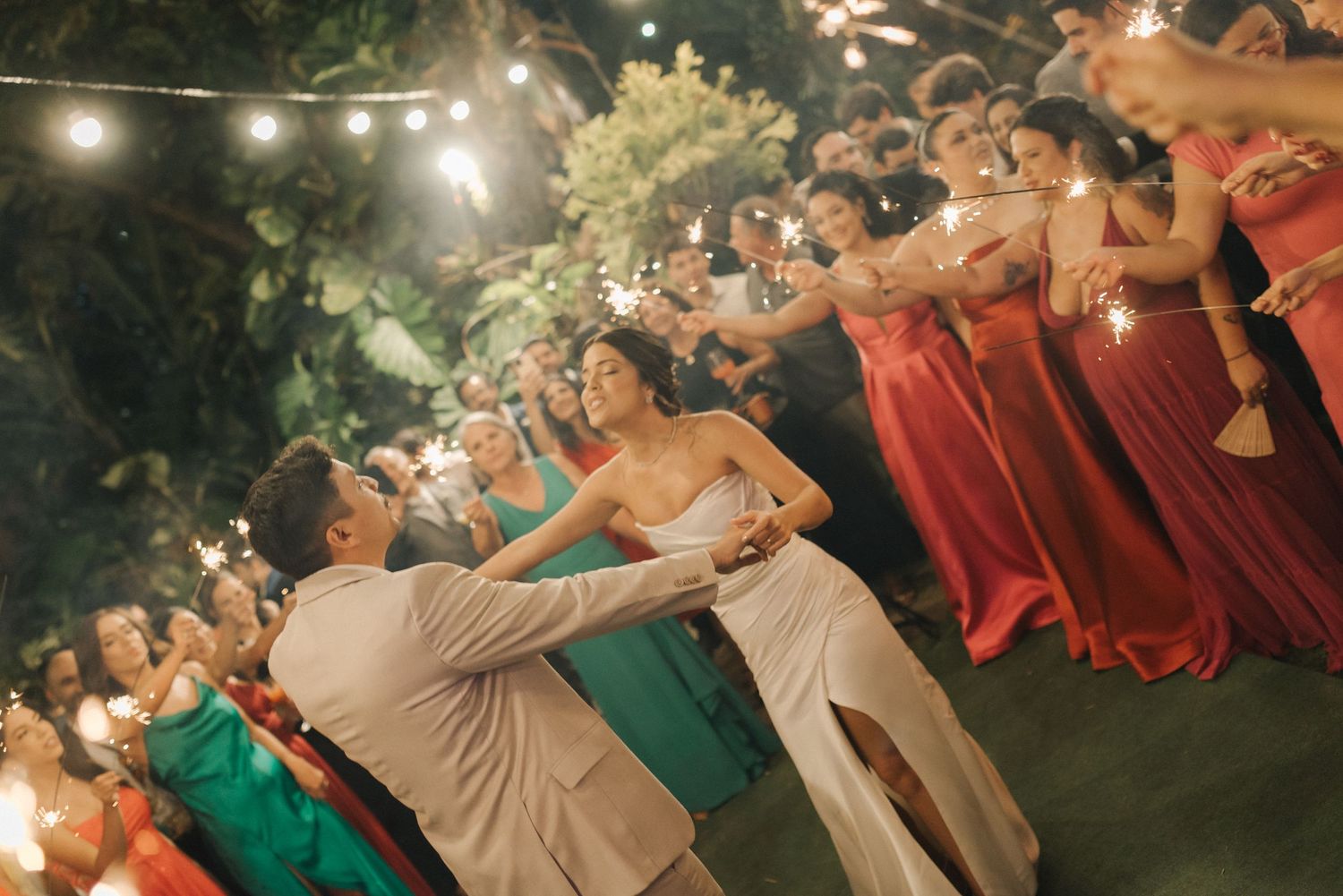 A joyful dance moment at an evening wedding reception with string lights overhead.