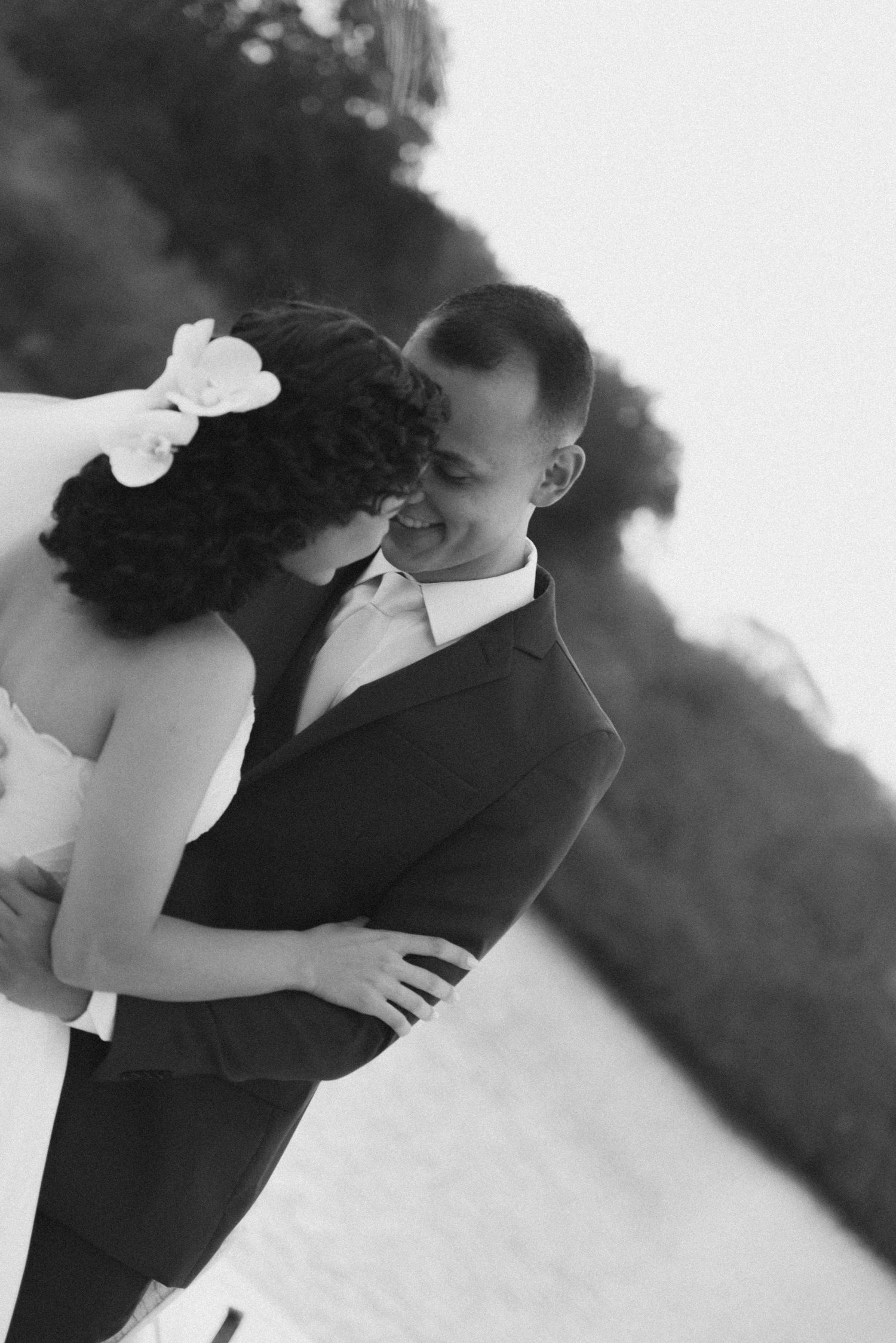 An intimate black and white portrait of a couple sharing a tender moment.