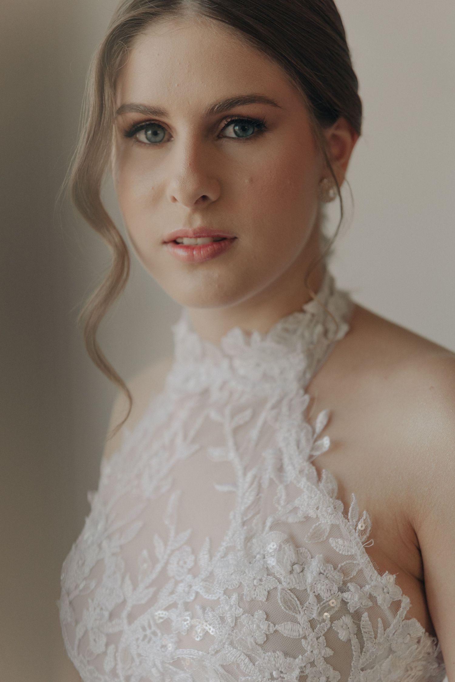 Close-up bridal portrait featuring delicate lace halter neckline and elegant makeup.