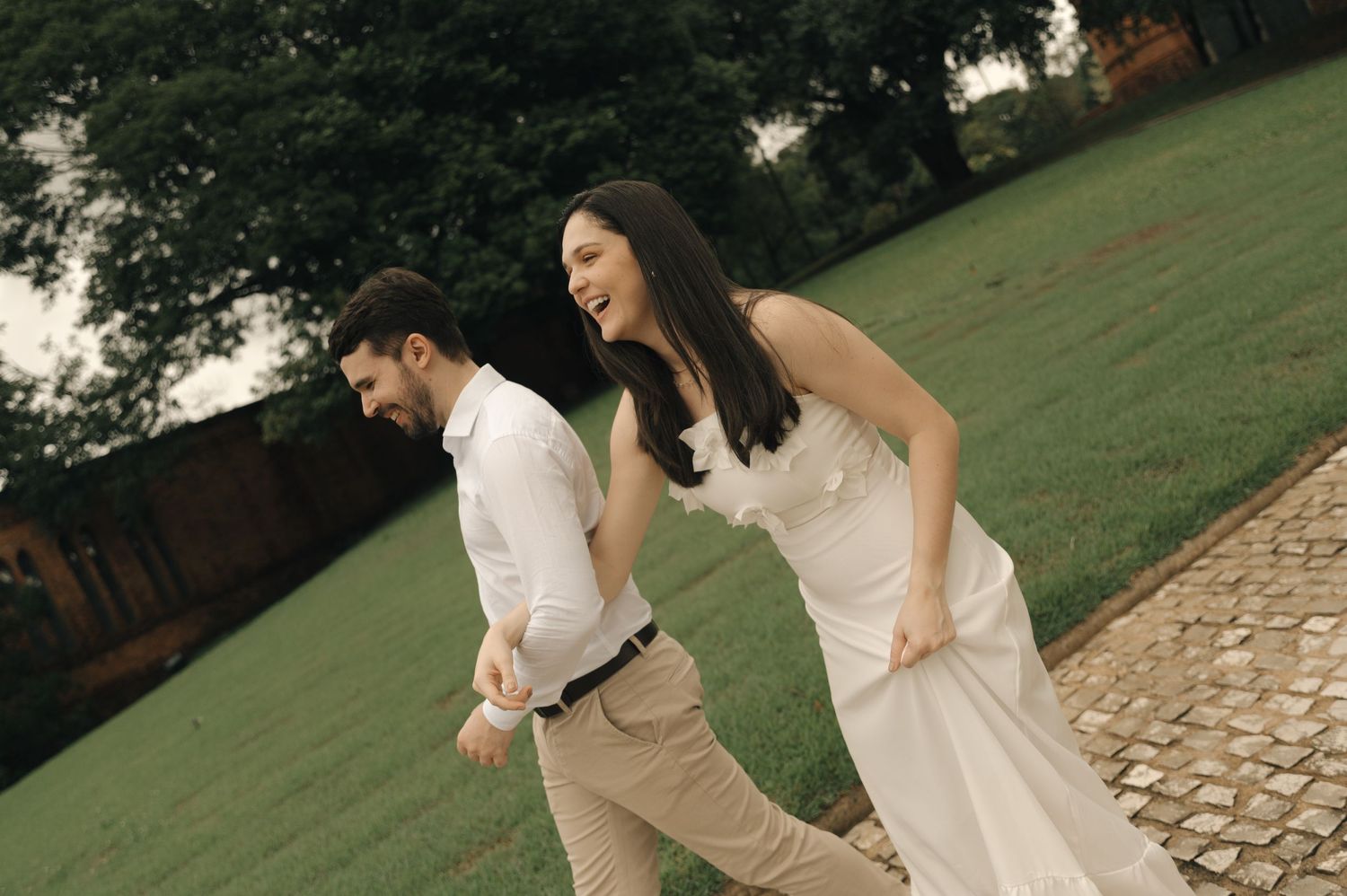 A romantic couple in wedding attire shares tender moments while walking through a lush garden setting.