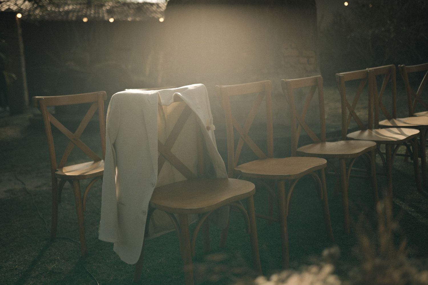 Rustic wooden chairs and tables arranged in an empty restaurant with soft, moody lighting.