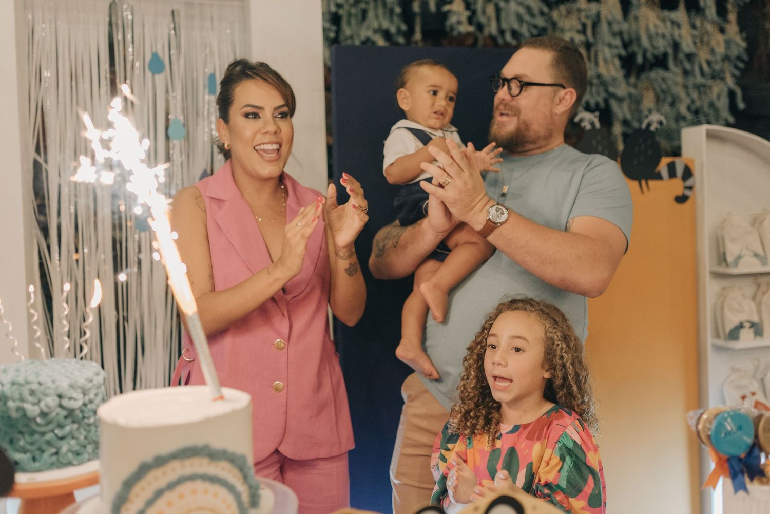 Family celebrating with sparklers and cake at festive party.