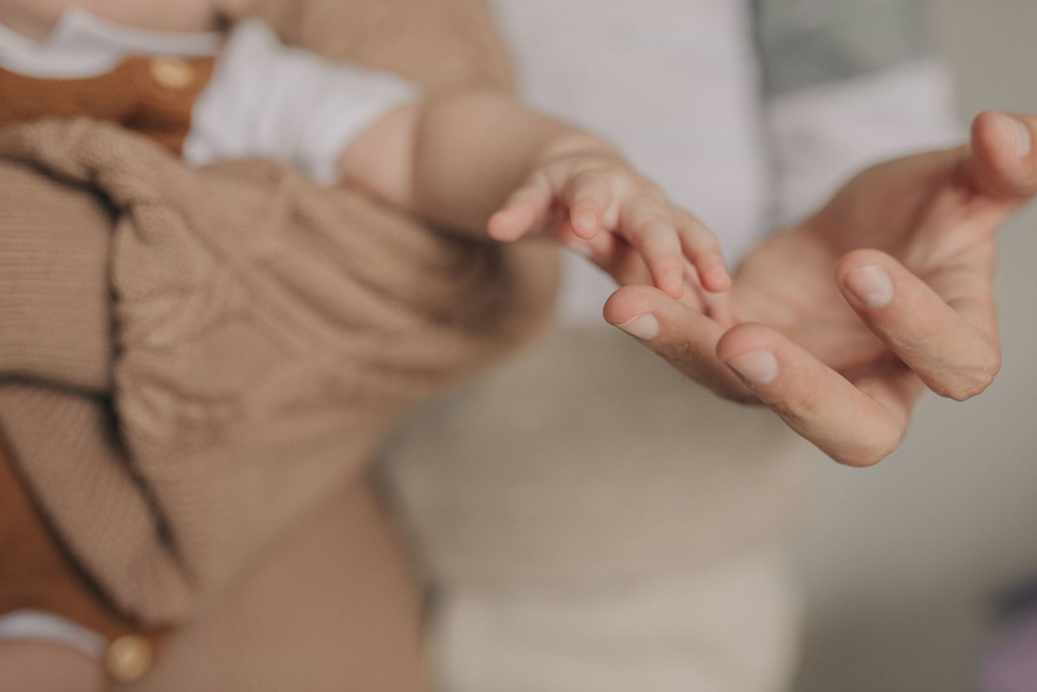 Close up photograph of small baby hands reaching out in soft lighting.