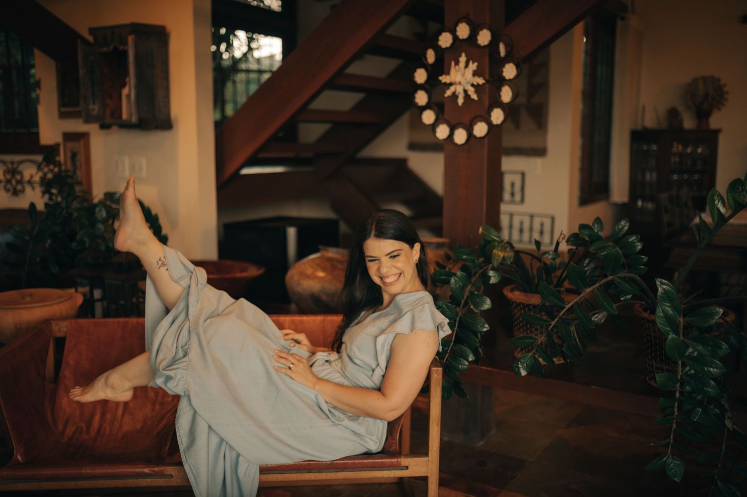 Playful lounging pose in a cozy living room with vintage decor and warm lighting.