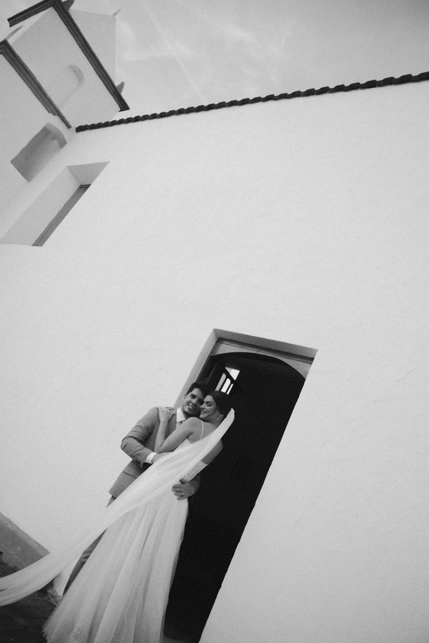 Black and white architectural photo of a bride standing in a doorway.