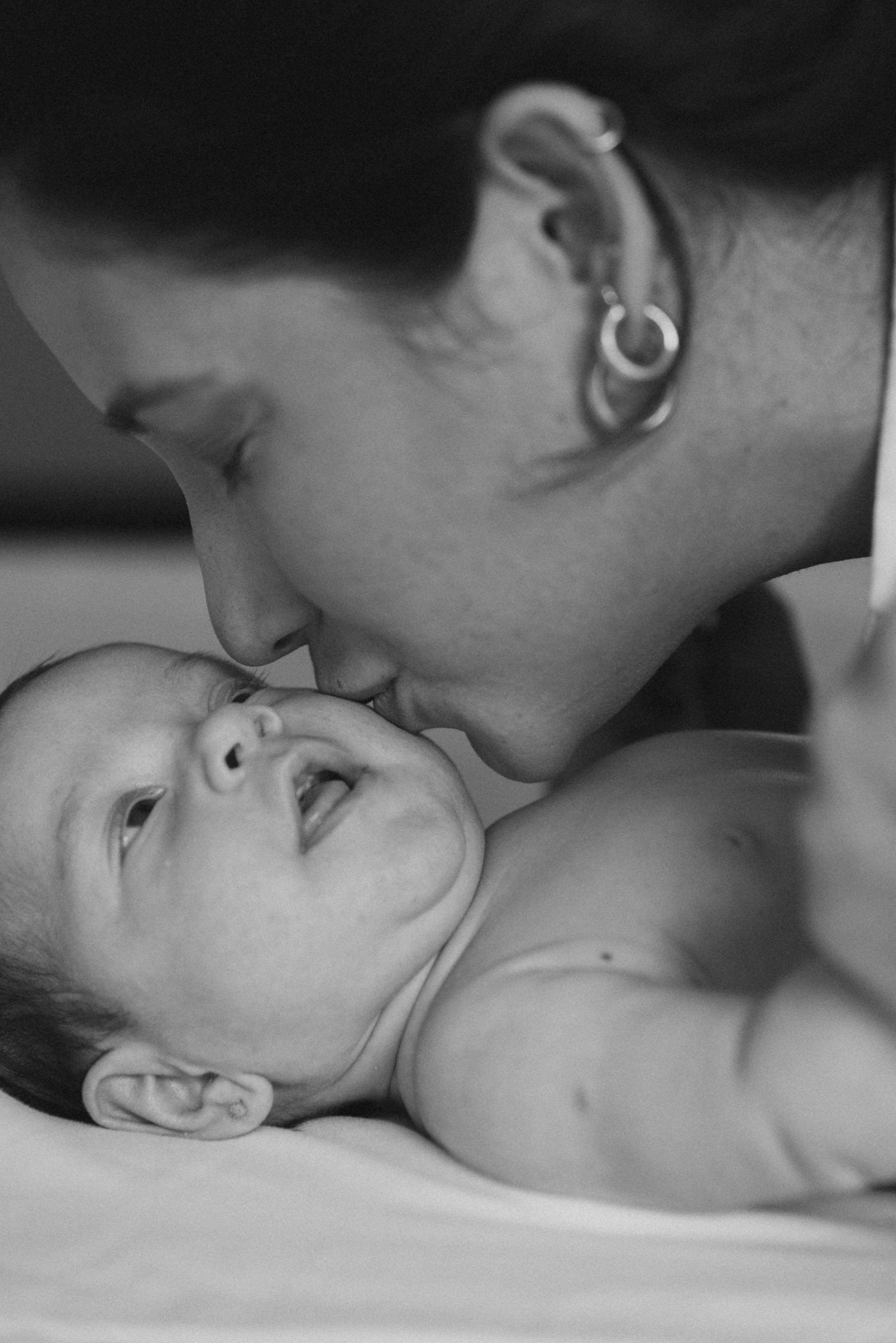 Black and white close-up photograph capturing a tender moment between parent and infant.