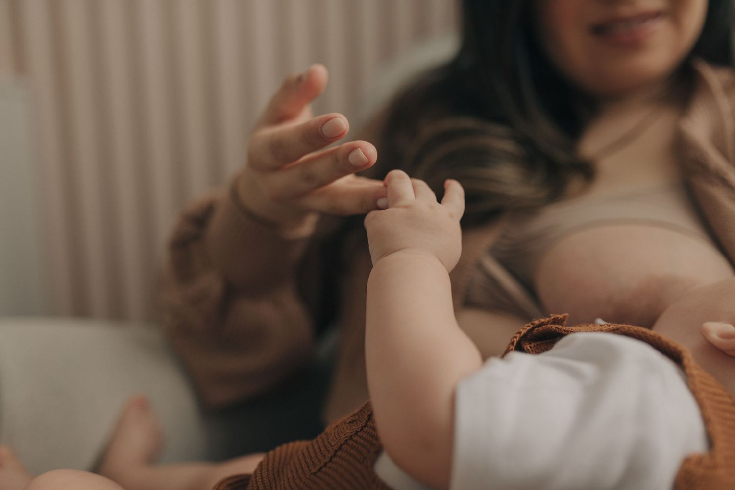 A close-up shot of tiny baby hands reaching out toward an adult's hands in a gentle gesture.