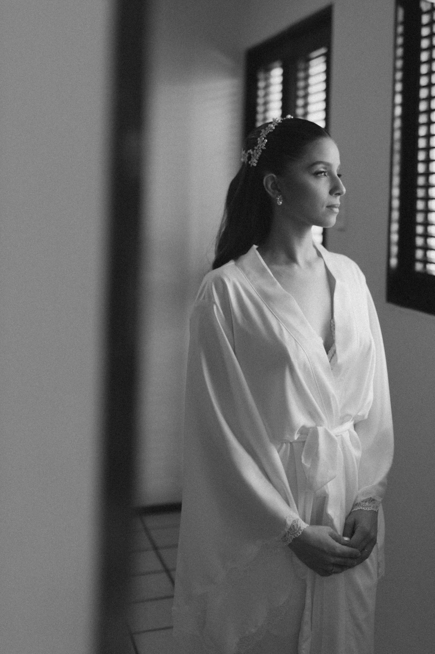 Elegant black and white portrait in a white robe with natural window lighting.