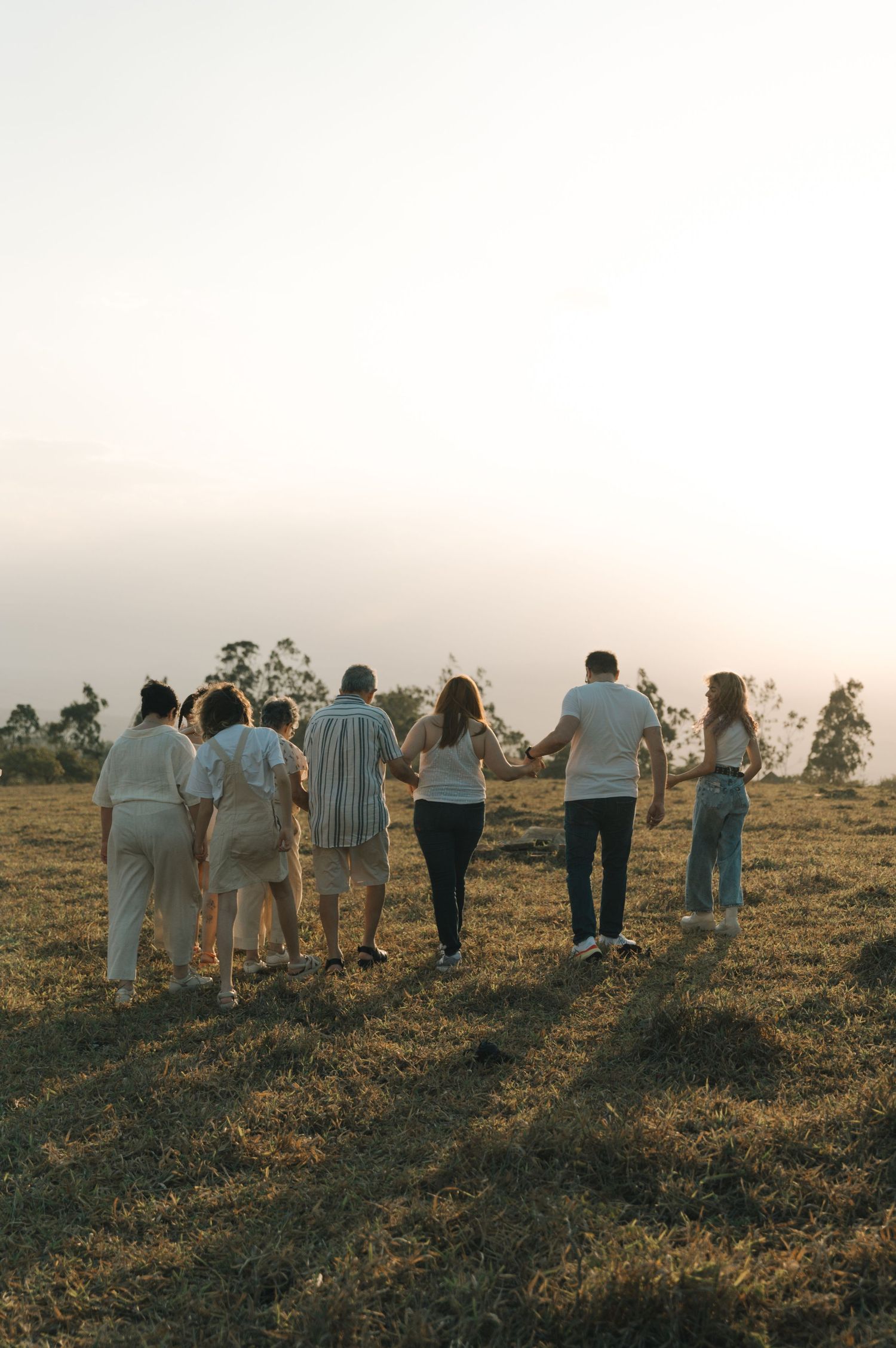 A group of people walking together on a grassy hillside during golden hour.