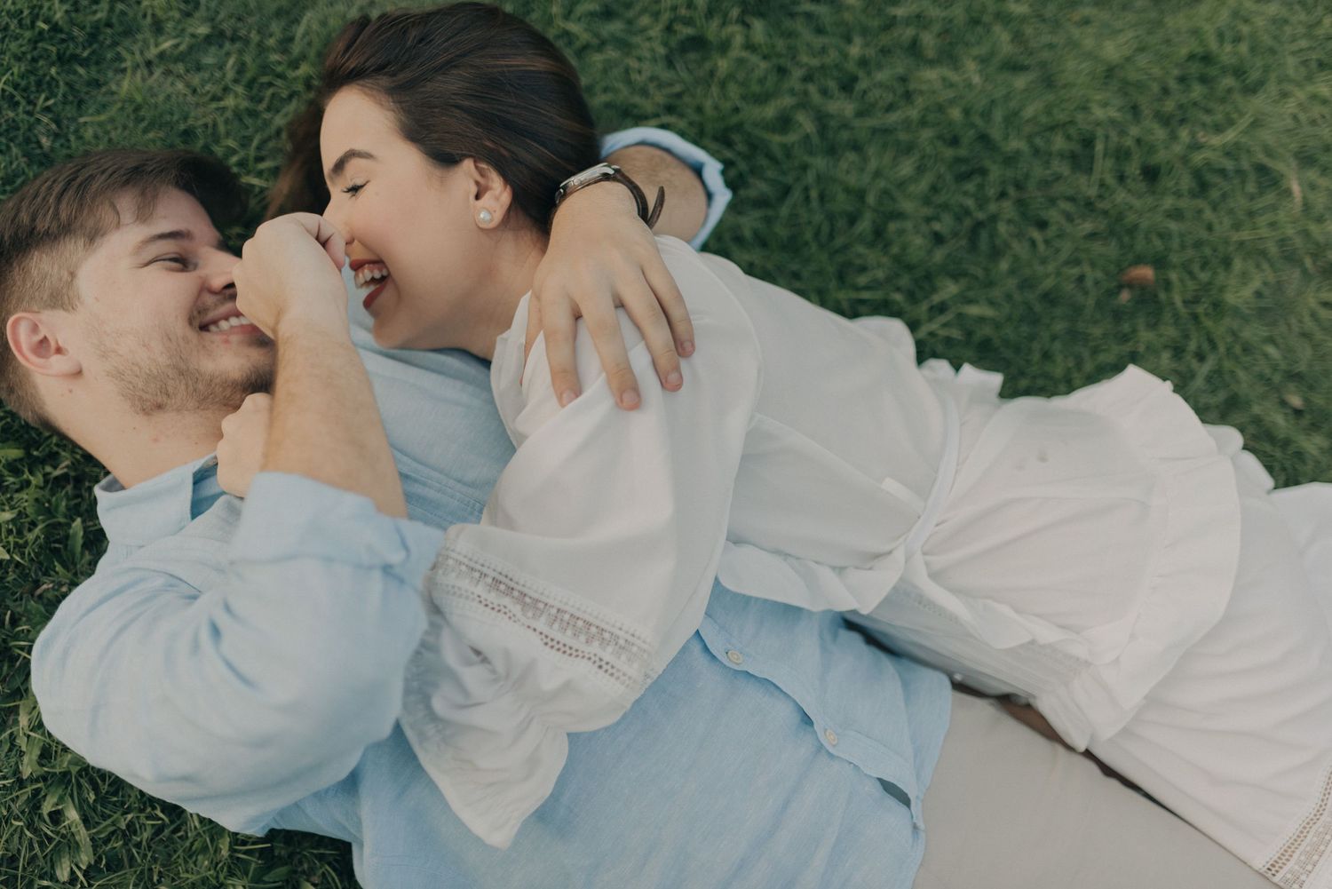 Intimate moment of couple in casual attire embracing on grass.