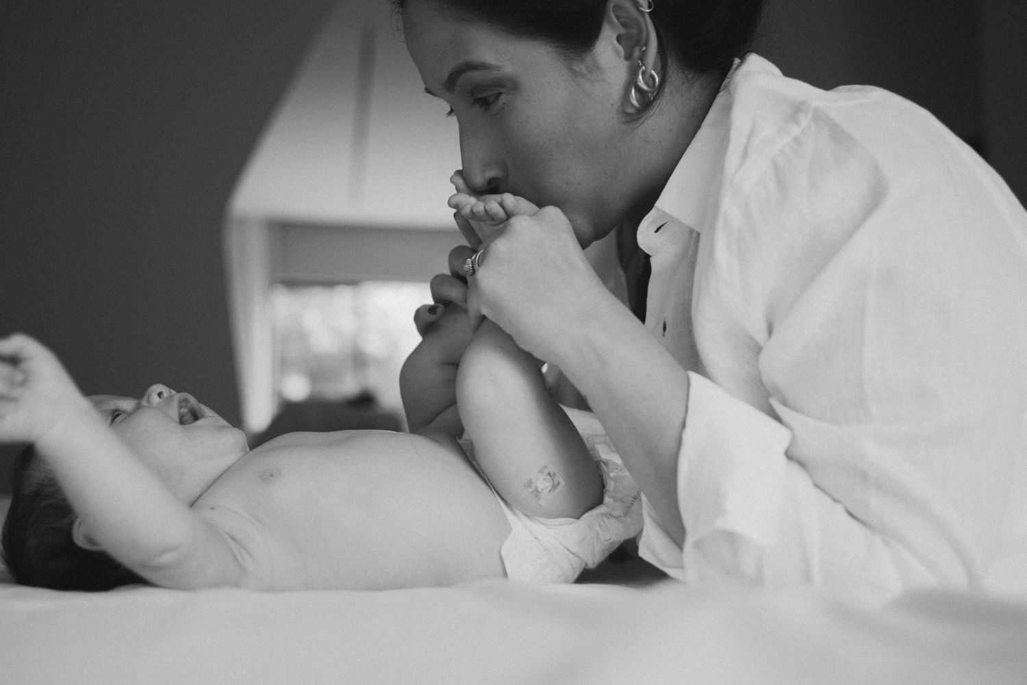 Black and white intimate moment of parent kissing baby's feet.