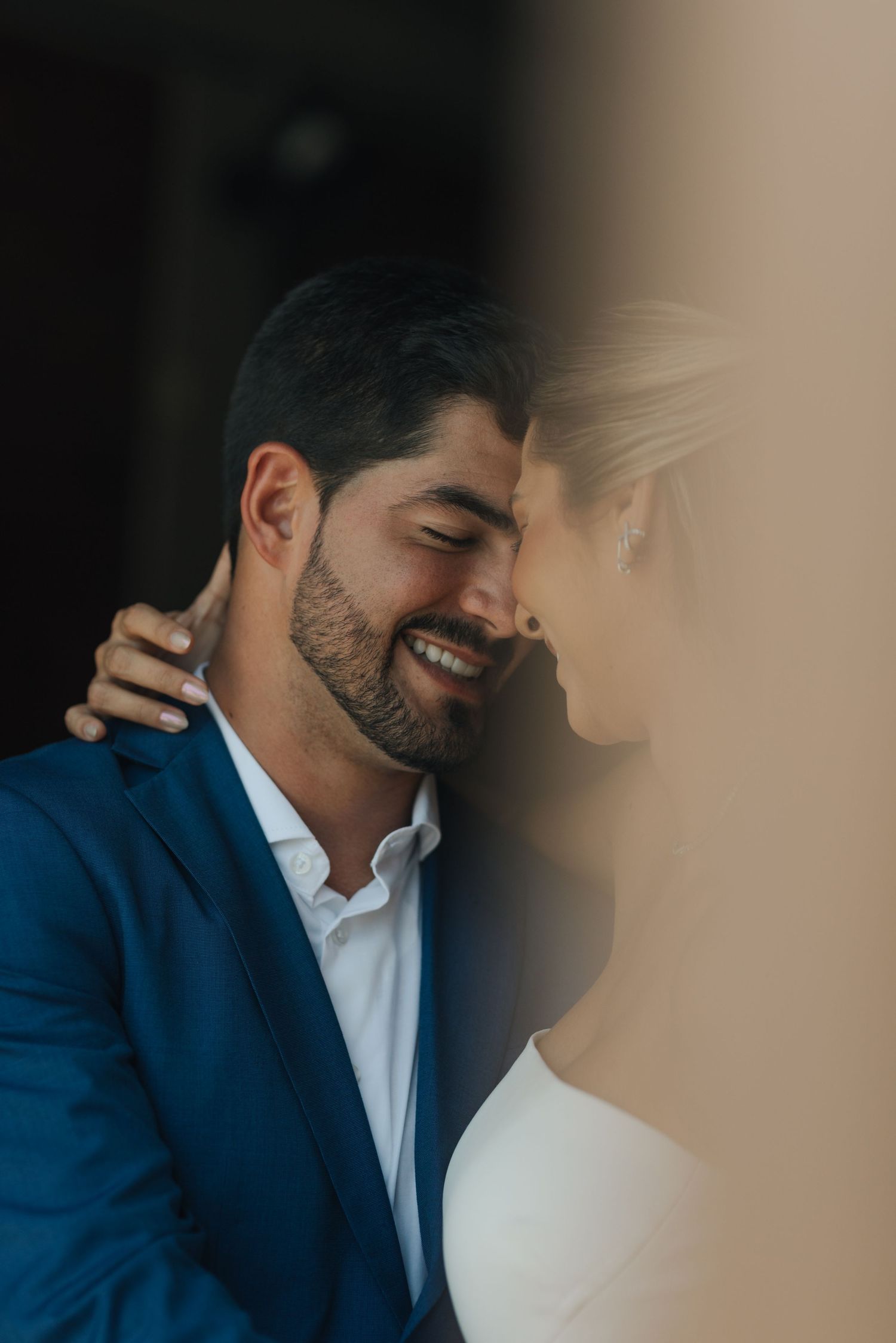 Intimate close-up of wedding couple sharing a tender moment against a neutral background.