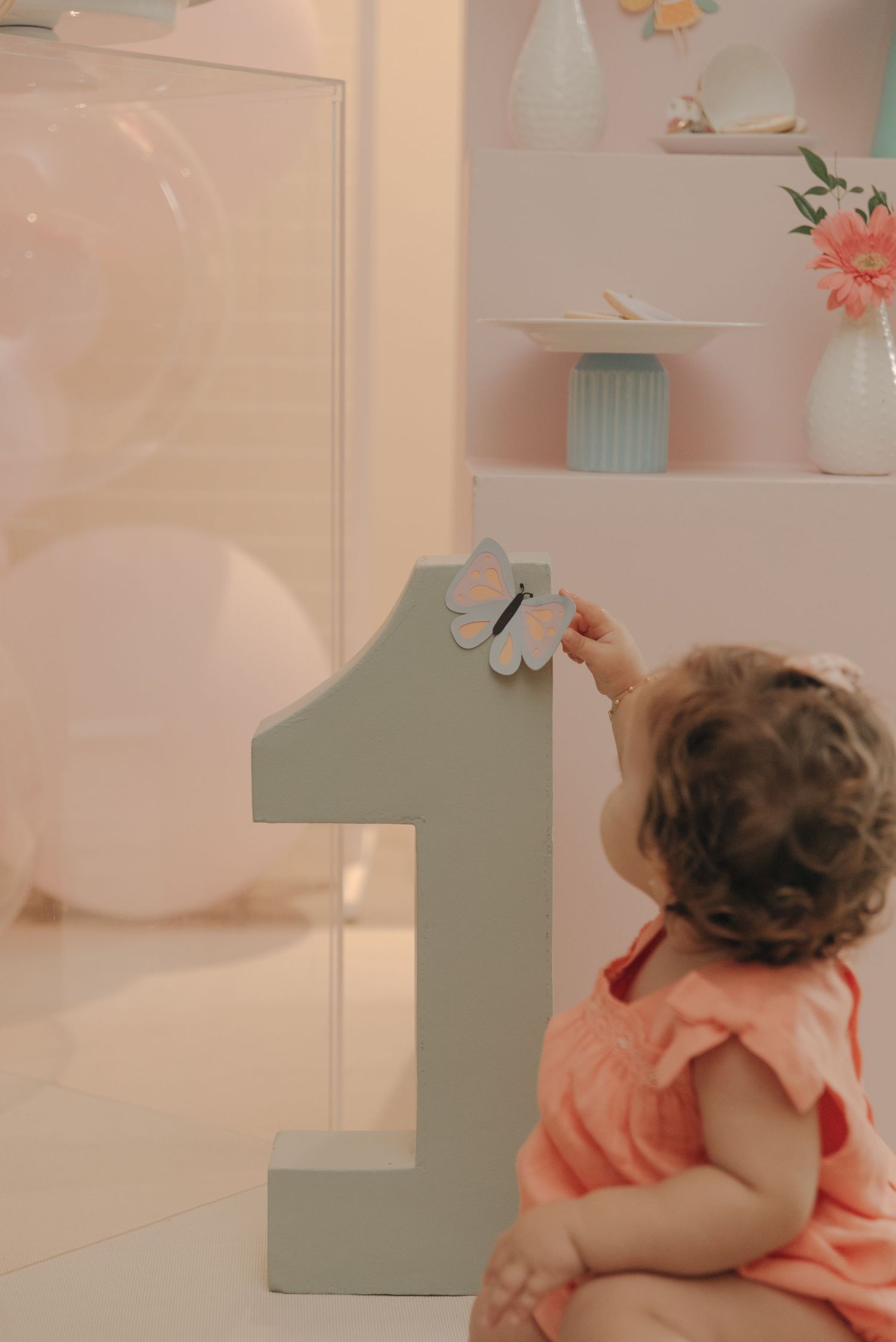 Gray number one decoration against a pink wall with shelving.