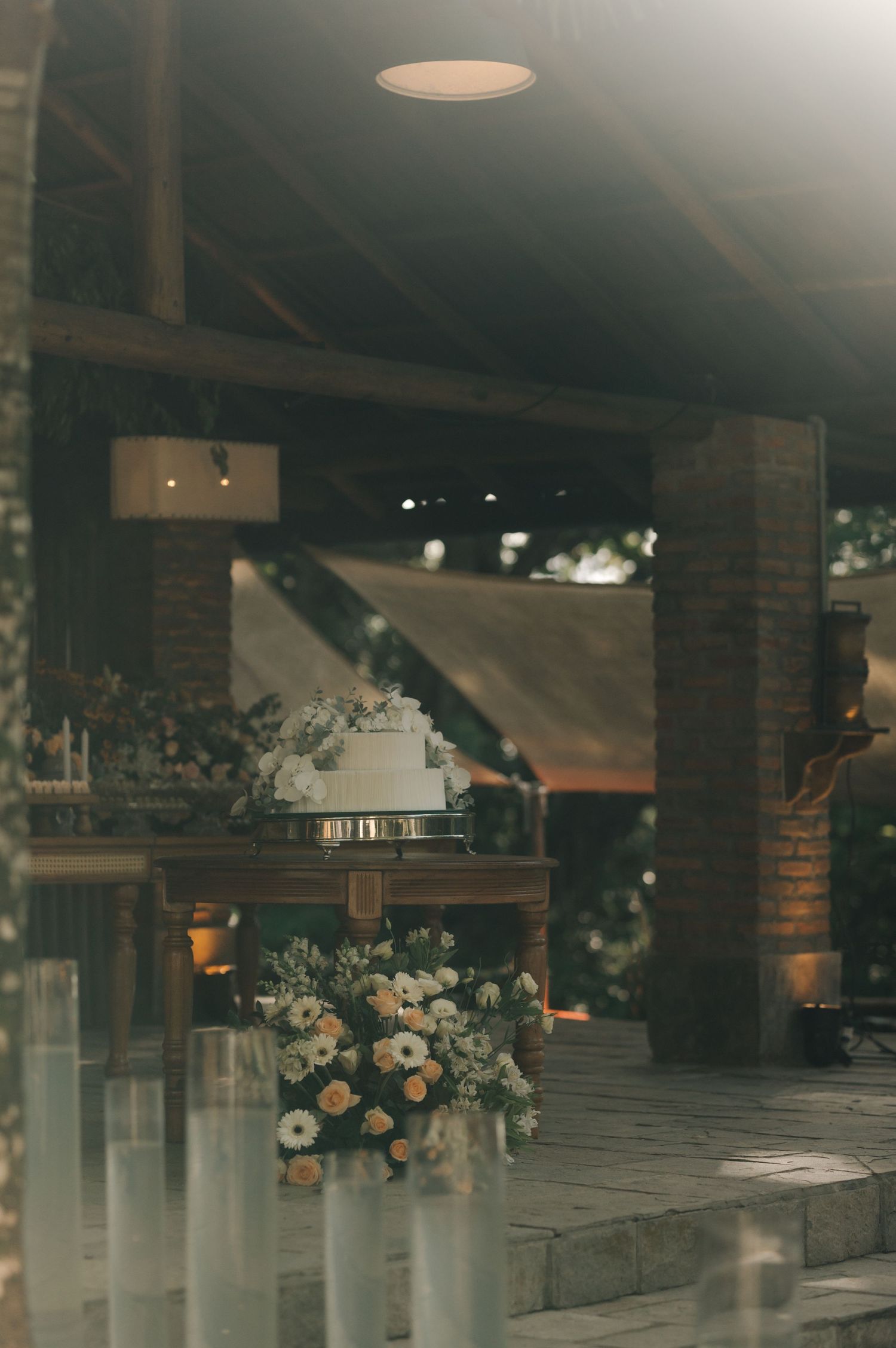 Vintage-style wedding venue entrance with brick columns and floral arrangements in soft lighting.
