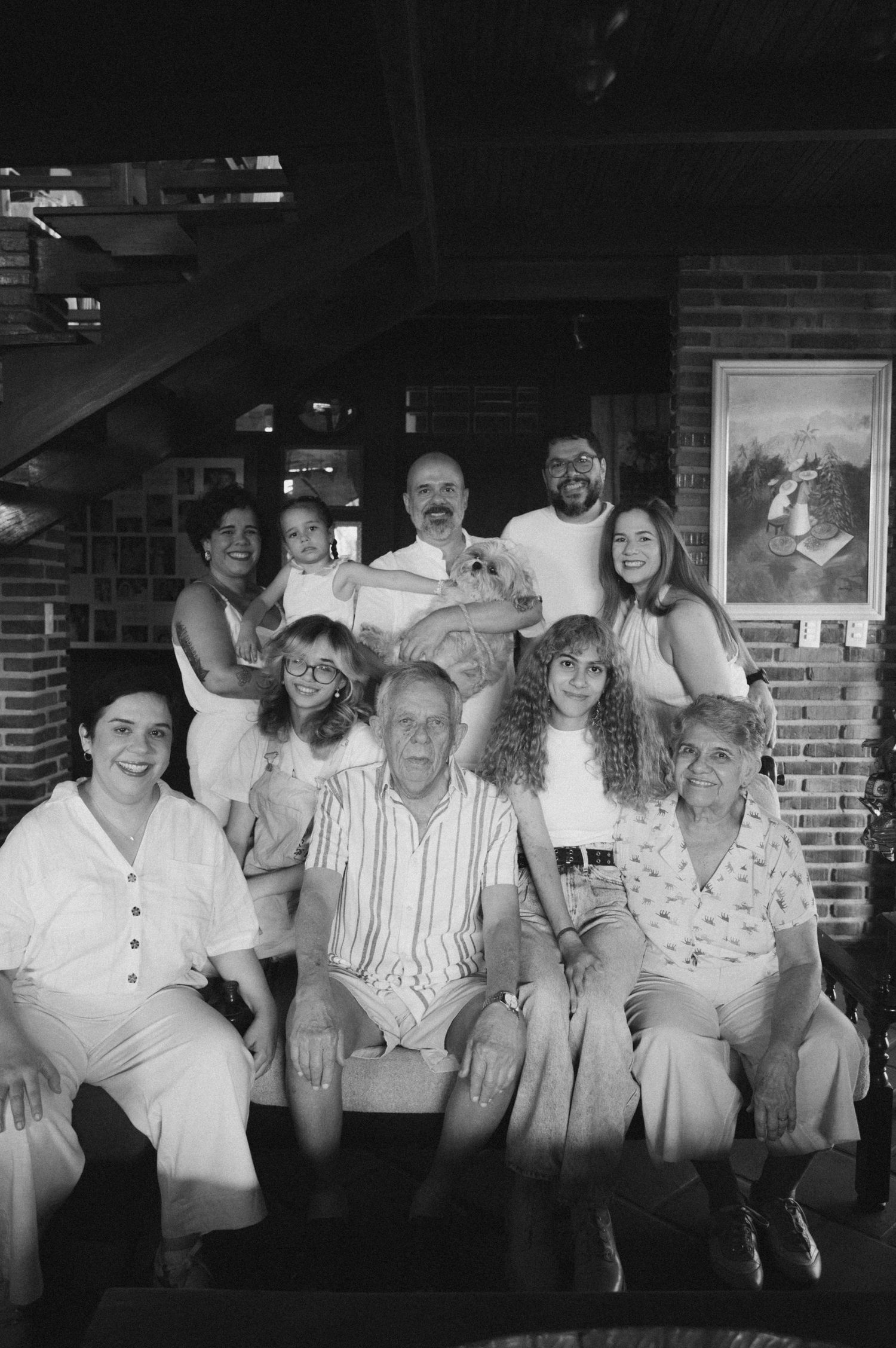 A vintage black and white photograph showing a group of people sitting together and smiling at a gathering.
