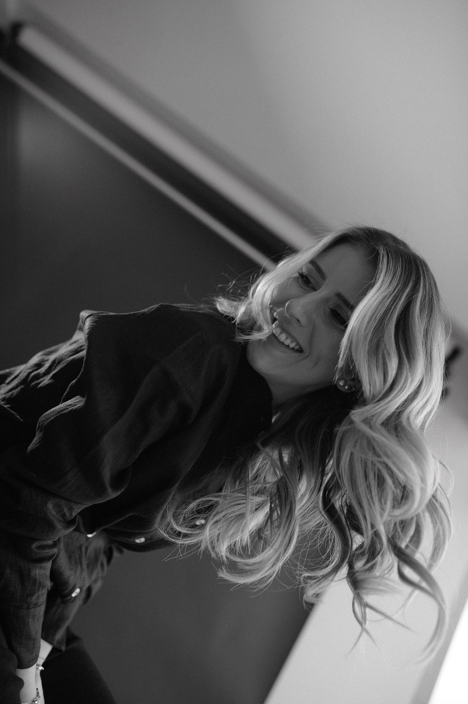 Black and white candid portrait showing joyful laughter in studio setting.