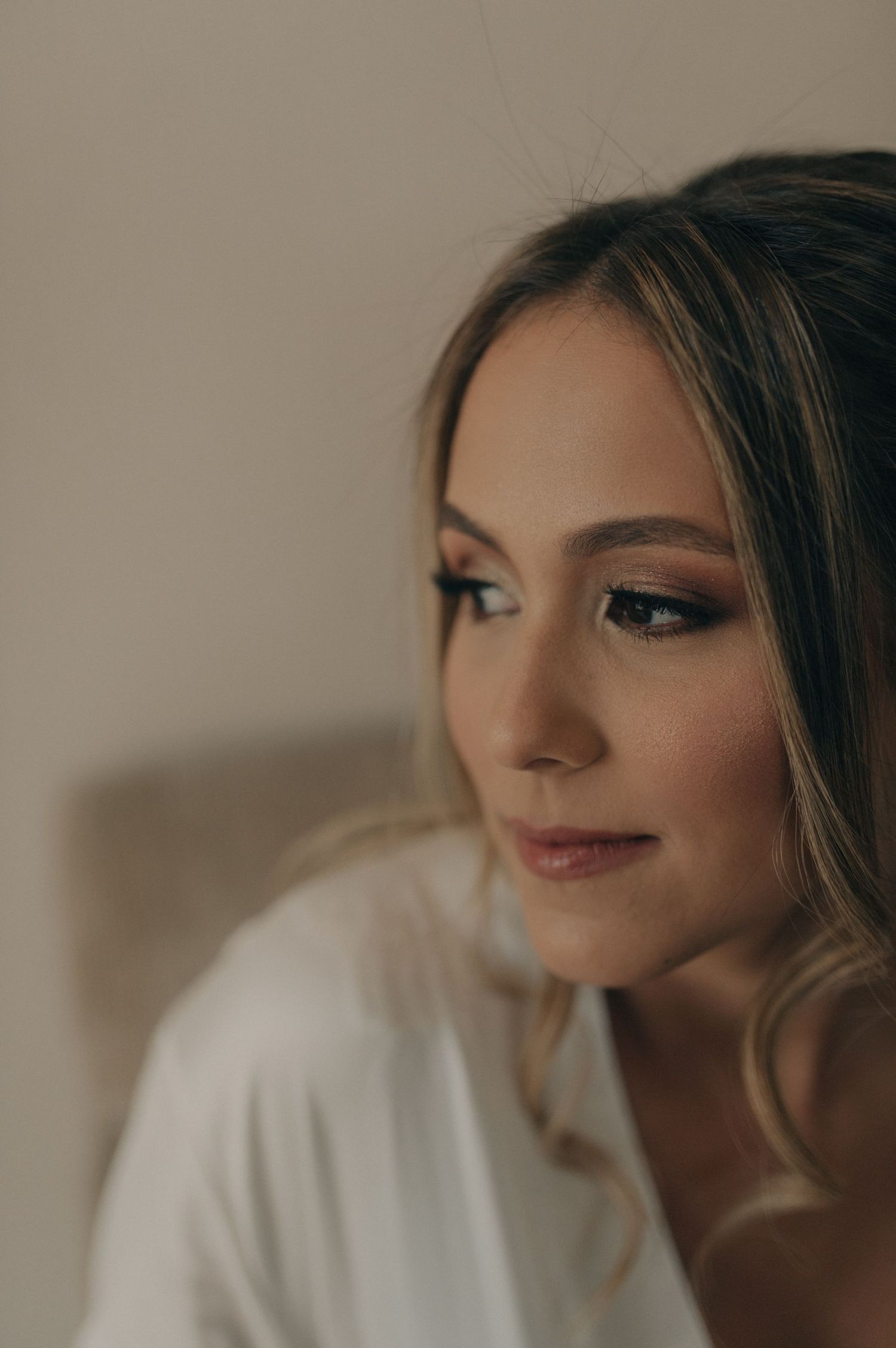 A romantic portrait in warm lighting shows a woman in soft makeup gazing to the side.